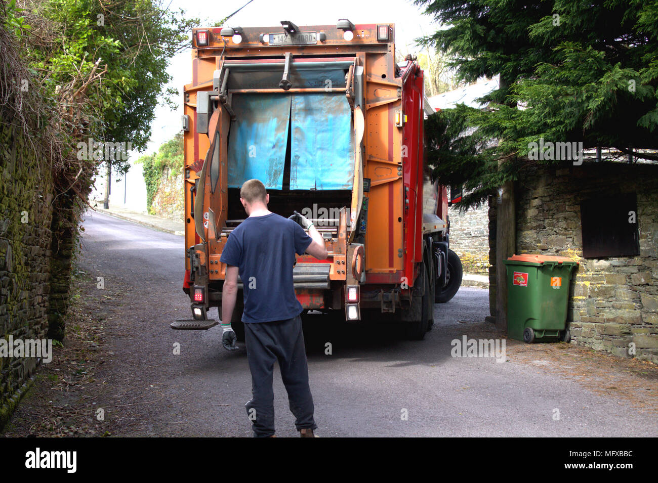 Jungen Erwachsenen männlichen Führen einer Mülltonne Sammlung Lkw, Lkw, dass die Umkehr in eine schmale Straße, vor der Erfassung der Müll, Müll. Stockfoto