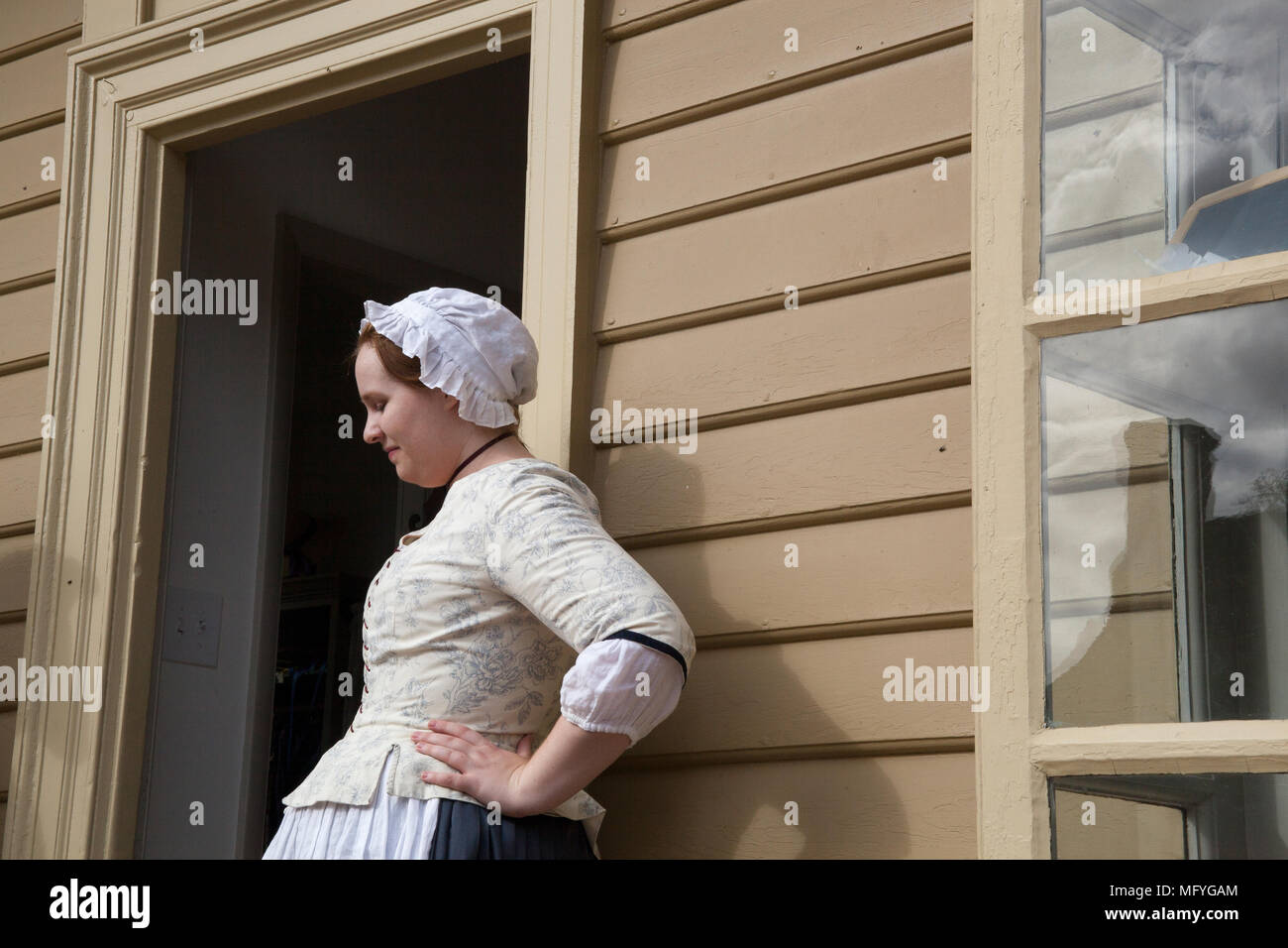 Frau in der frühen amerikanischen Kostüm in der Tür stehen einer schalbrett Gebäude auf Herzog von glouchester Straße Colonial Williamsburg Virginia Stockfoto