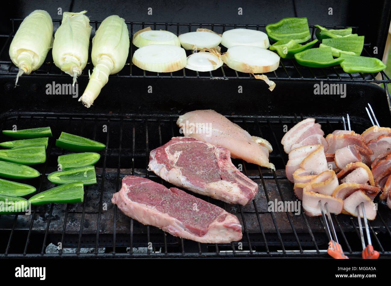 Steaks, Paprika, Zwiebeln und Mais werden auf einem Grillrestaurant im Freien für ein köstliches Sonntagsessen zubereitet Stockfoto