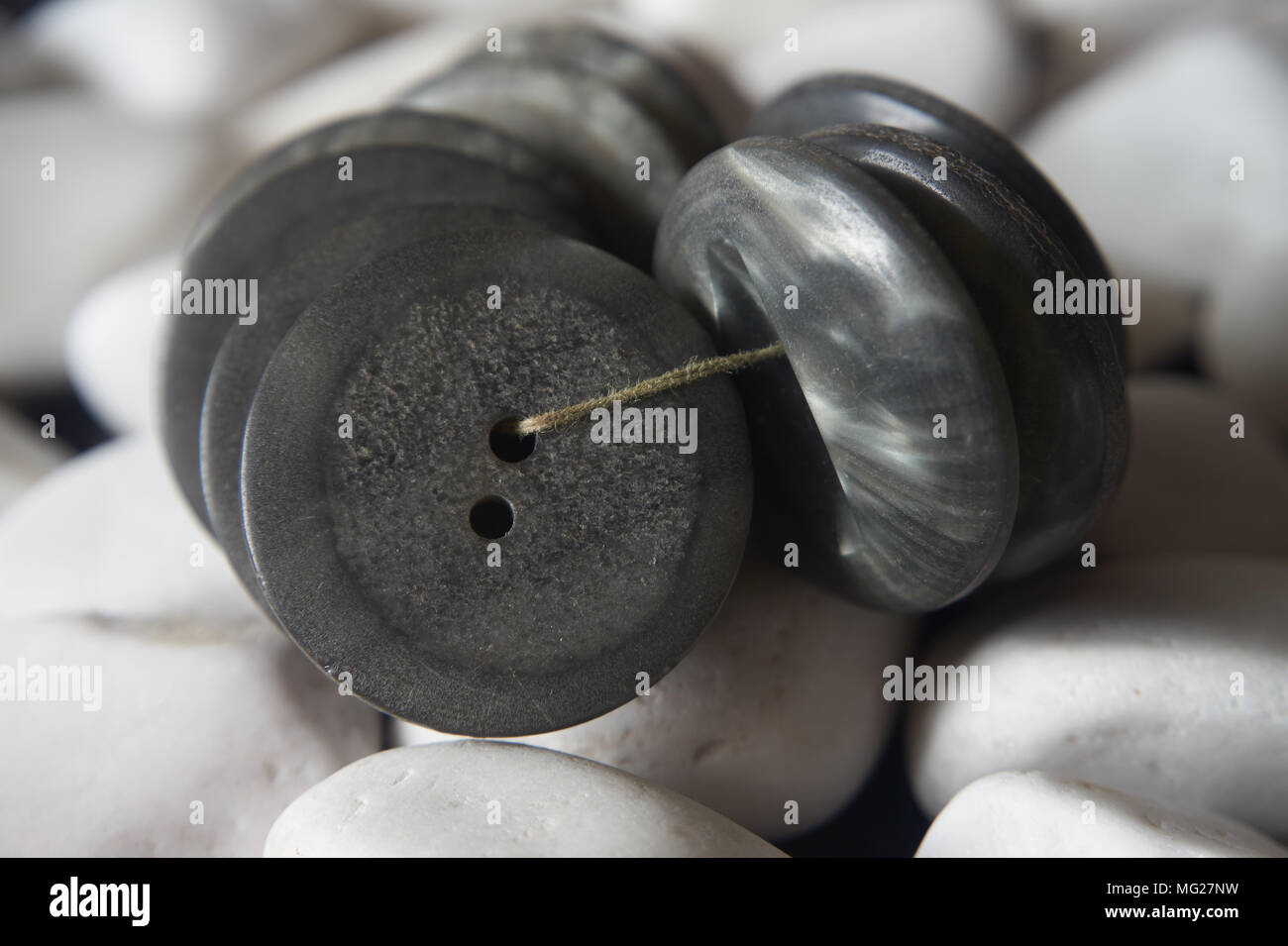 Bündel von grauen Tasten mit Gewinde auf der weißen Steine Hintergrund gebunden. Makro, geringe Tiefenschärfe. Stockfoto