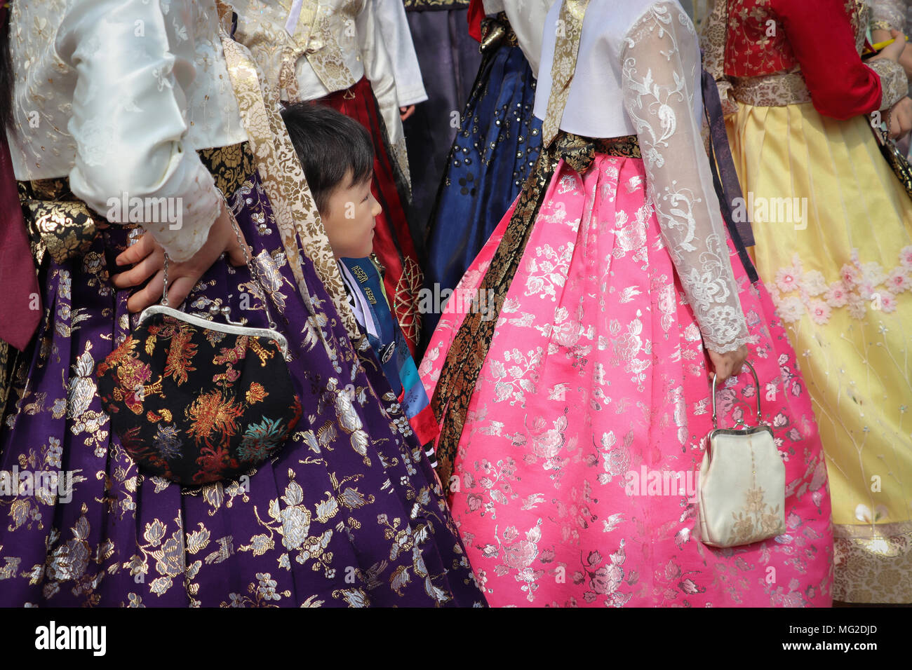 Ein kleiner Junge versteckt sich unter die Röcke in einer Gruppe von koreanischen Frauen das Tragen der traditionellen hanbok Mode, in brillanten Farben. Angesehen Schultern nach unten. Stockfoto