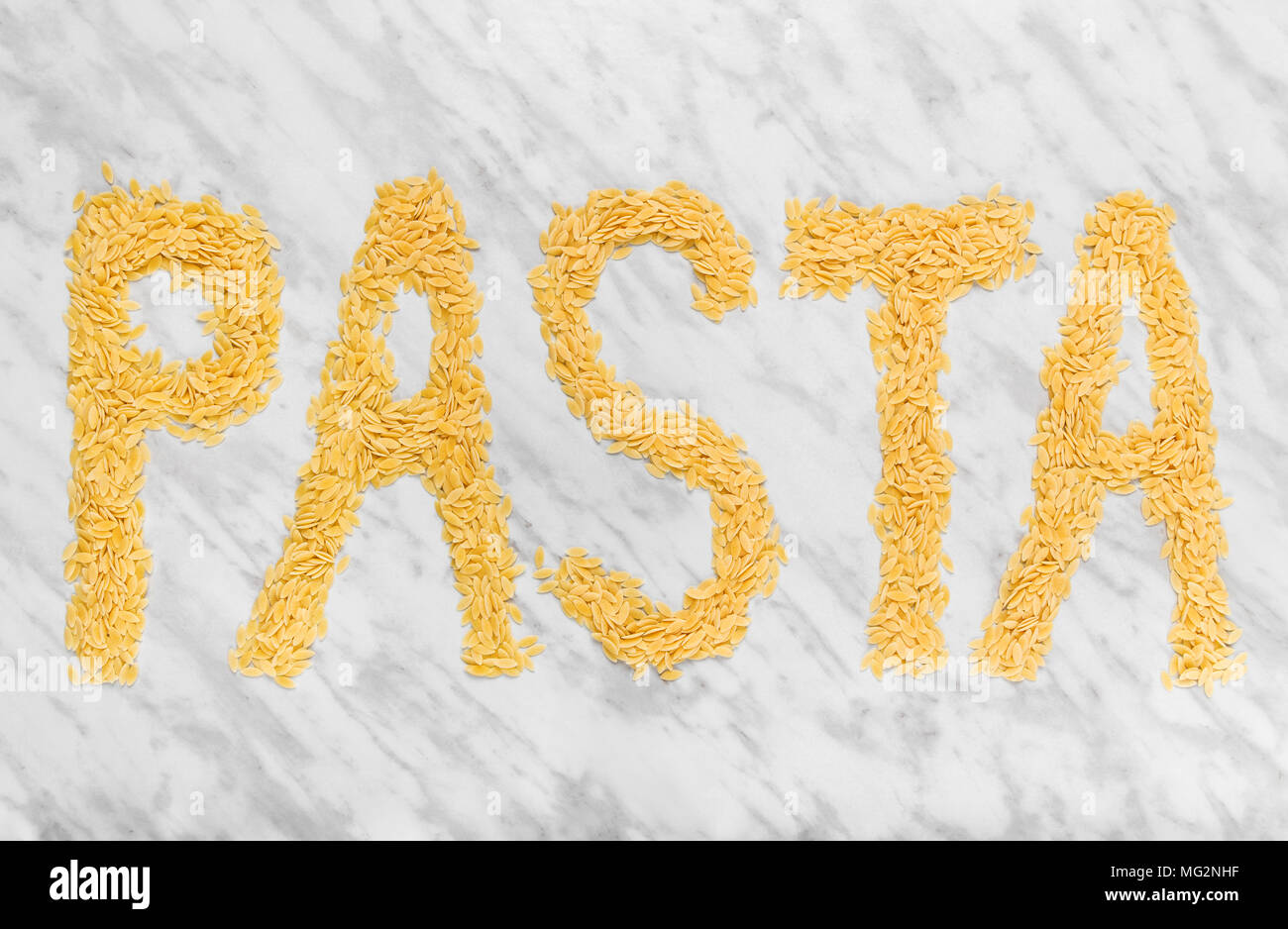 Das Wort "PASTA" auf Marmor Hintergrund, mit Reis-förmige winzige Orzo pasta geschrieben. Stockfoto
