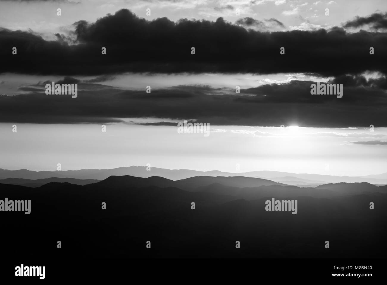 Sonnenuntergang über den Bergen in Umbrien, mit Sonne, die hinter einigen Wolken Stockfoto