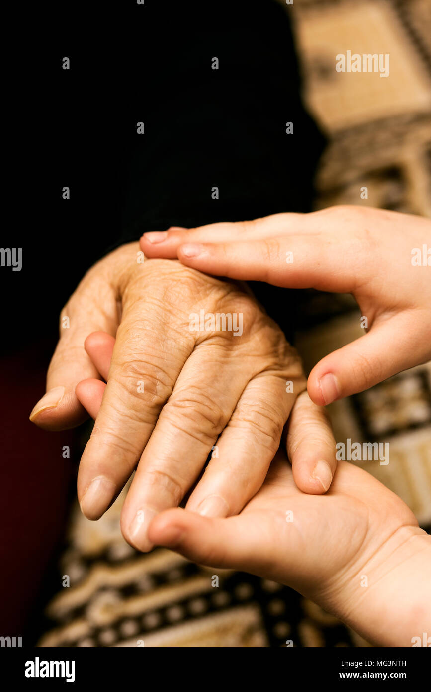 Kleines Kind streichelt die Hand der Großmutter Stockfoto