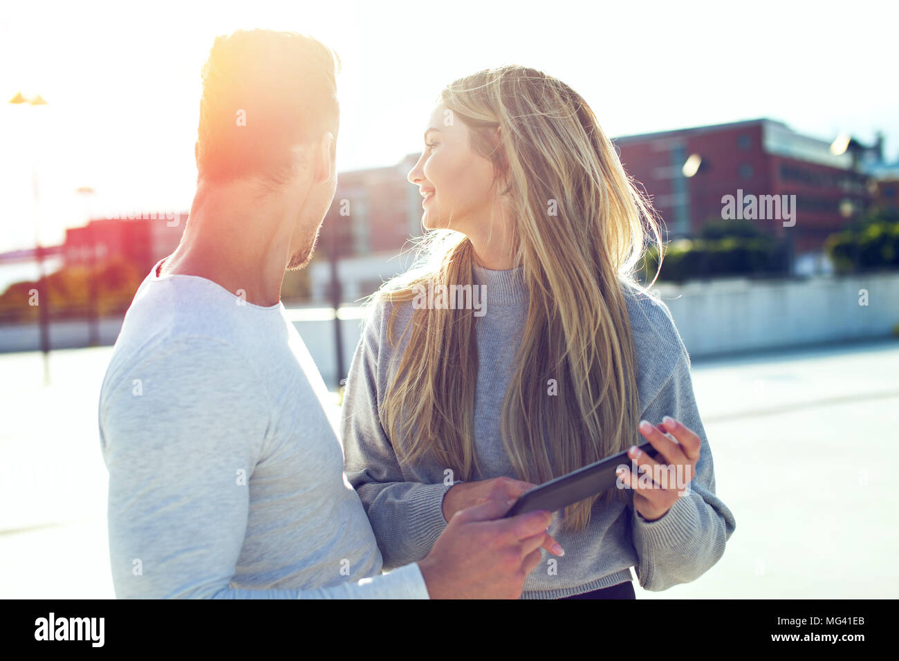Junge casual modernes Paar mit Tablet suchen zurück in den Sonnenuntergang im Freien Stockfoto
