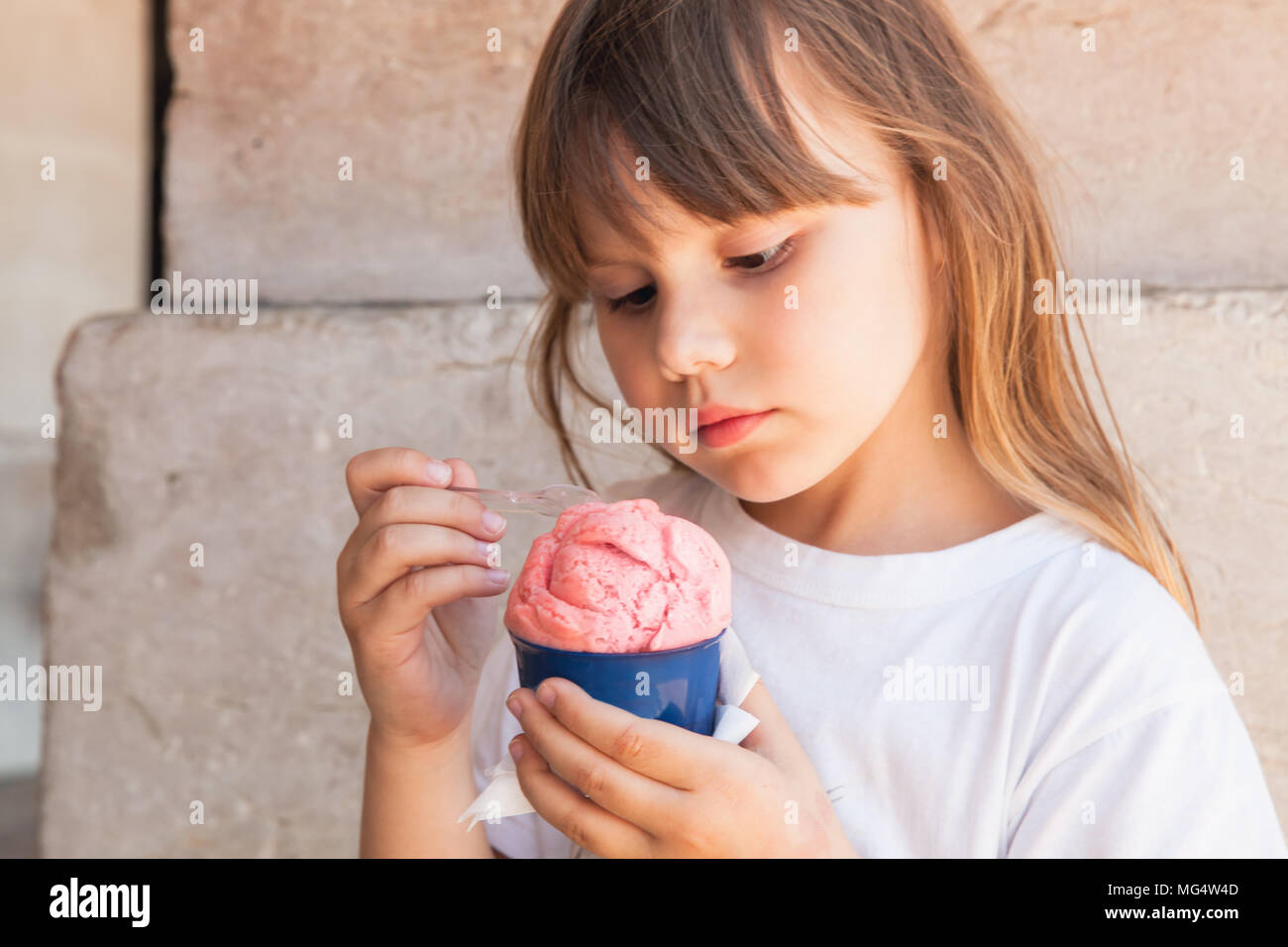 Kleine blonde Europäische Mädchen isst rosa Eis, bis Outdoor Portrait schließen Stockfoto