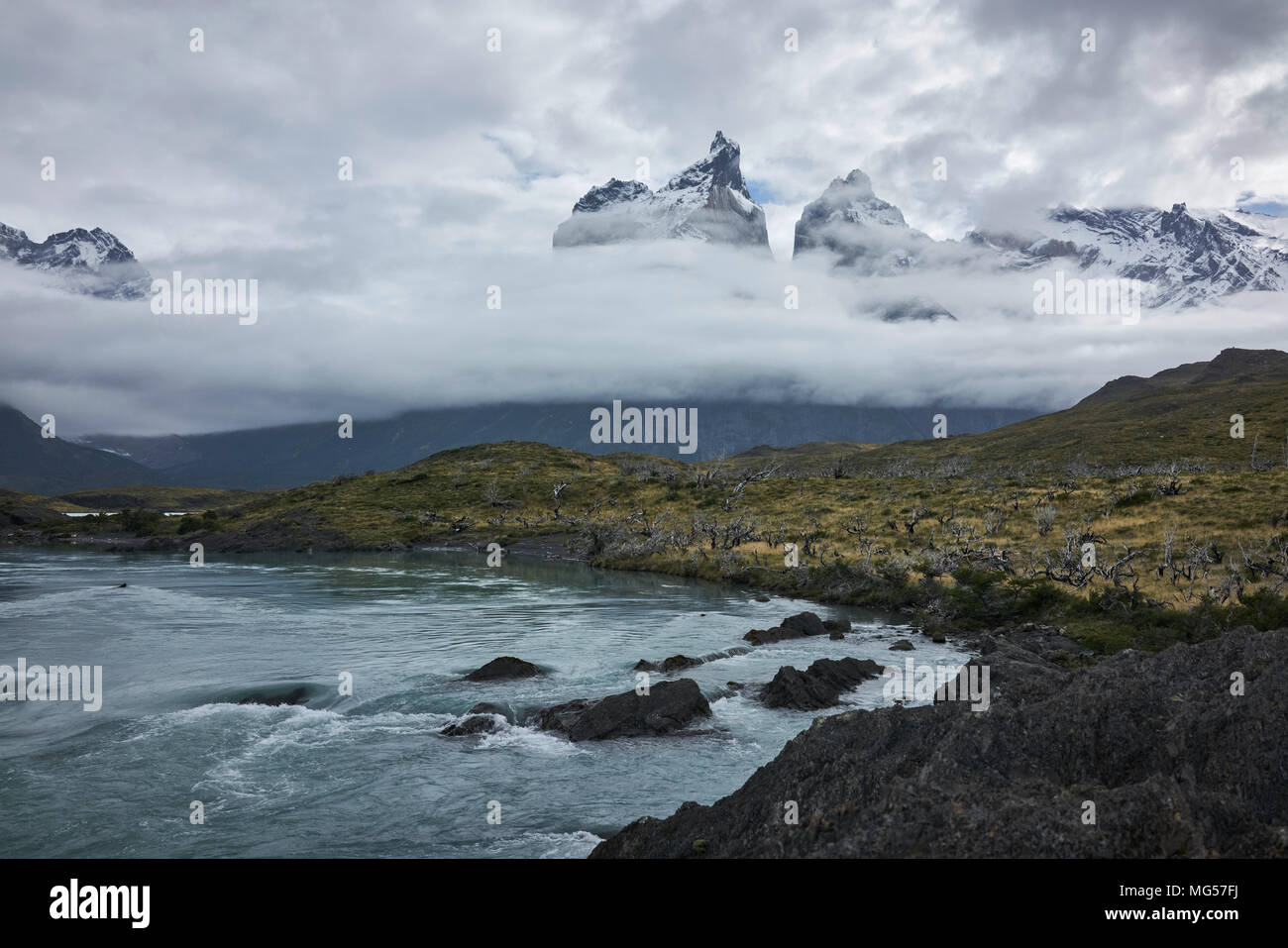 Cerro Paine Grande und die Gewässer des Paine Fluss im chilenischen Patagonien. Wolken bedecken die zerklüfteten Berge. Weite Einstellung. Panorama. Stockfoto