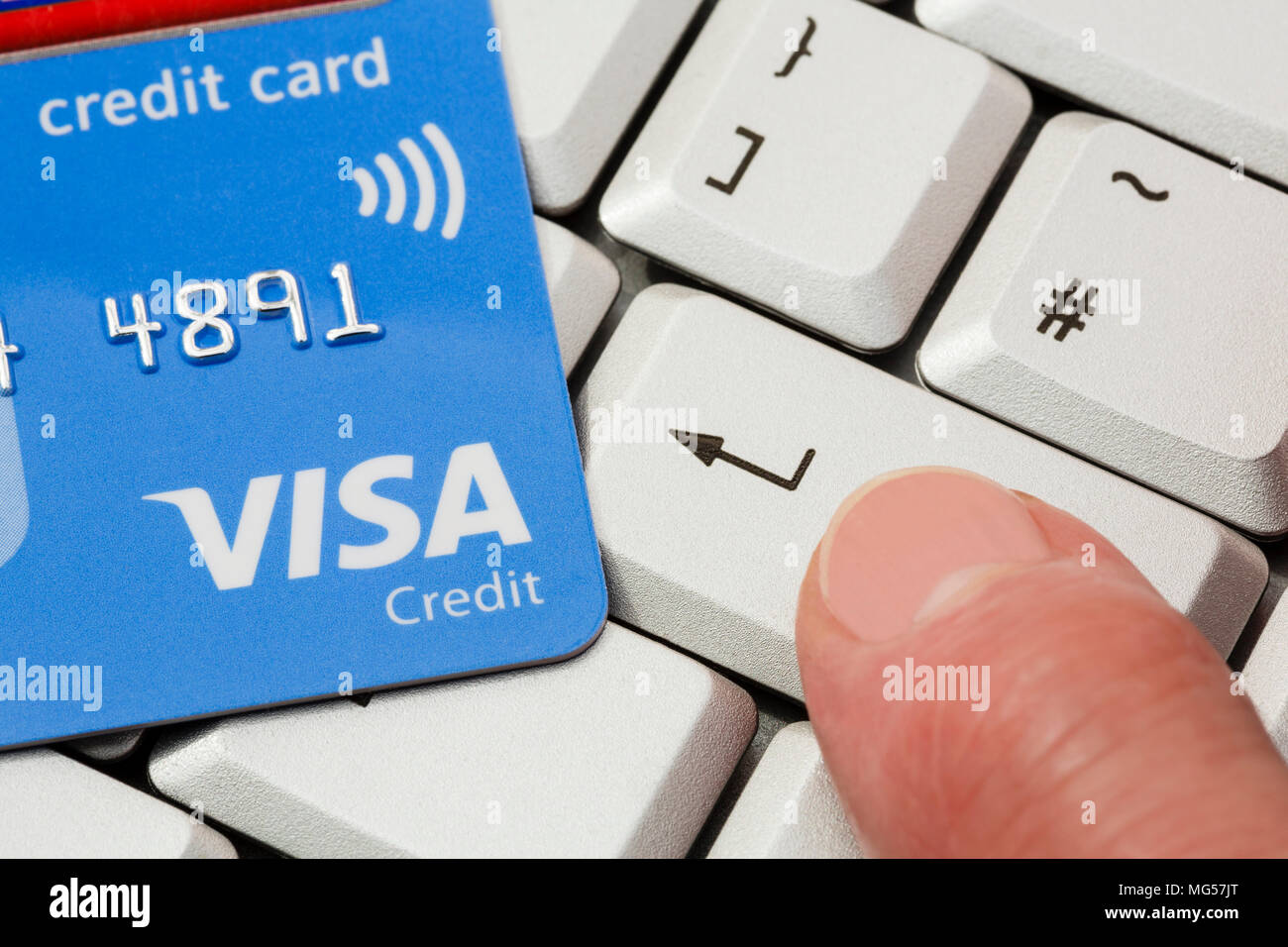 Kontaktlose Visa-Kreditkarte auf einer Tastatur mit dem Finger einer Person Drücken der Eingabetaste, um online mit Visa zu kaufen. Internet-Shopping-Konzept. England, Großbritannien Stockfoto