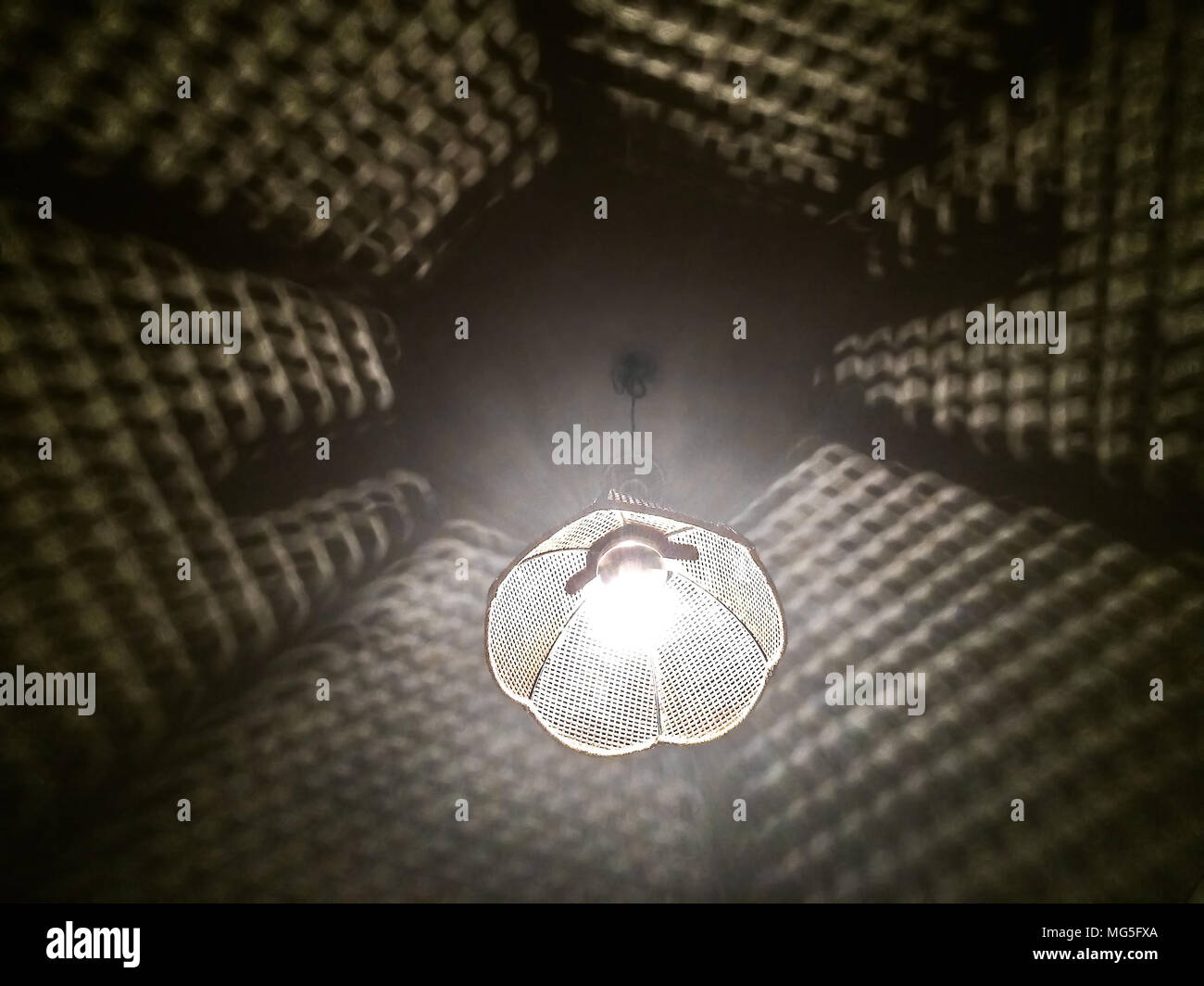 Eine helle Glühbirne und ein Lampenschirm vom Dach hängend erstellen Schatten mustern. Stockfoto