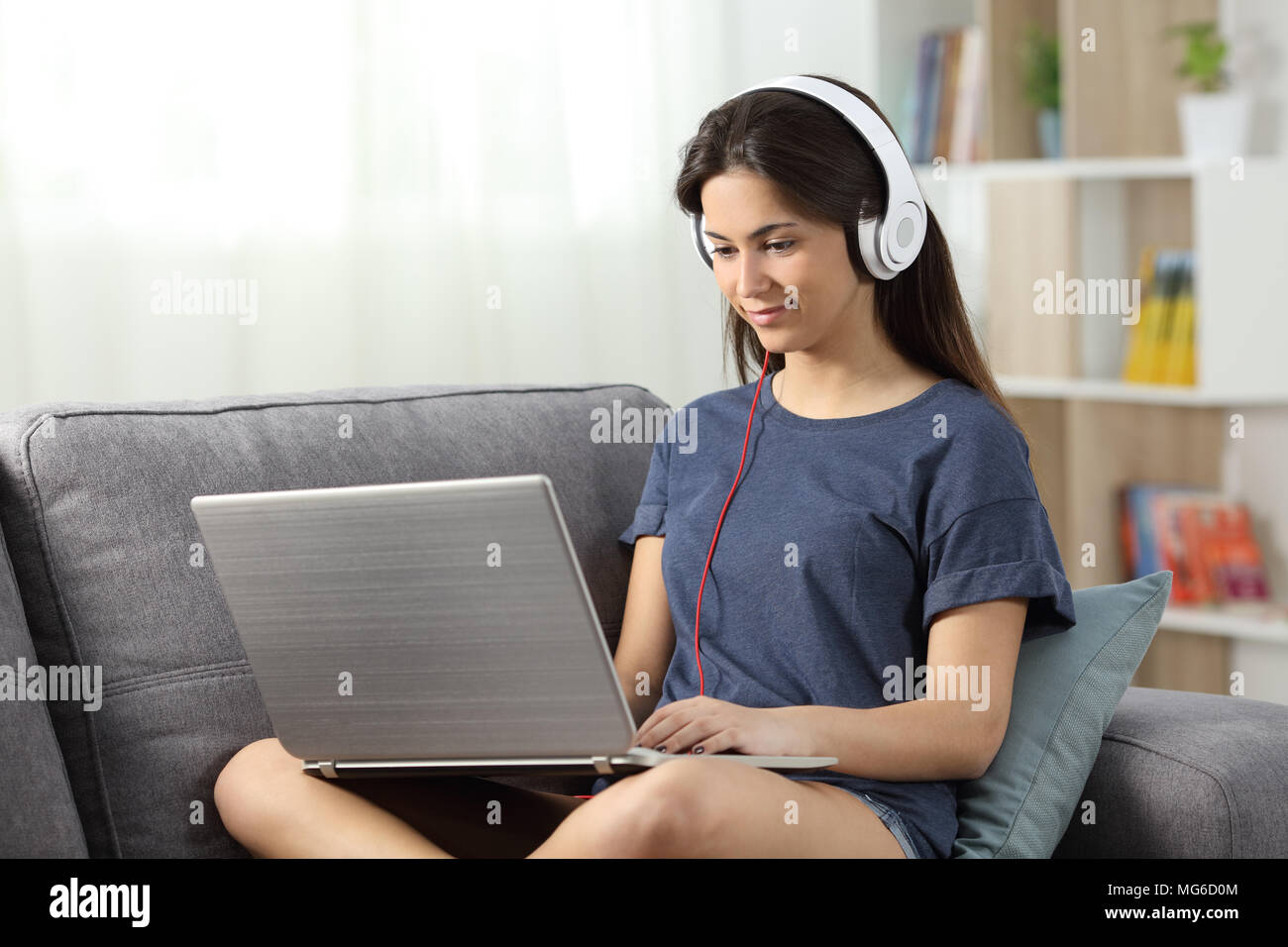 Jugendlich e-learning mit einem Laptop auf der Couch im Wohnzimmer zu Hause sitzen Stockfoto
