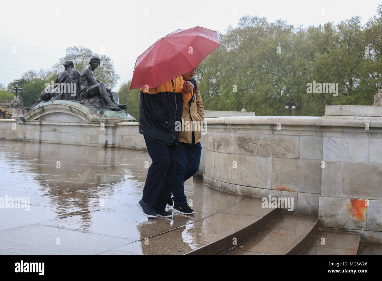 London, Großbritannien. 27. April 2018. Touristen Unterschlupf vor dem Regen vor dem Buckingham Palace auf einer nassen regnerischen Tag in London Stockfoto