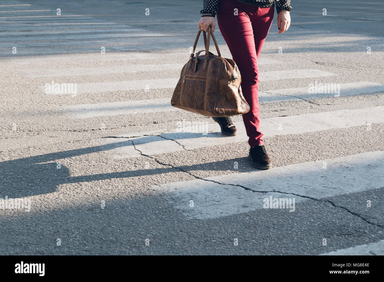Die Frau mit dem braunen Leder Tasche überquert einen Zebrastreifen Stockfoto