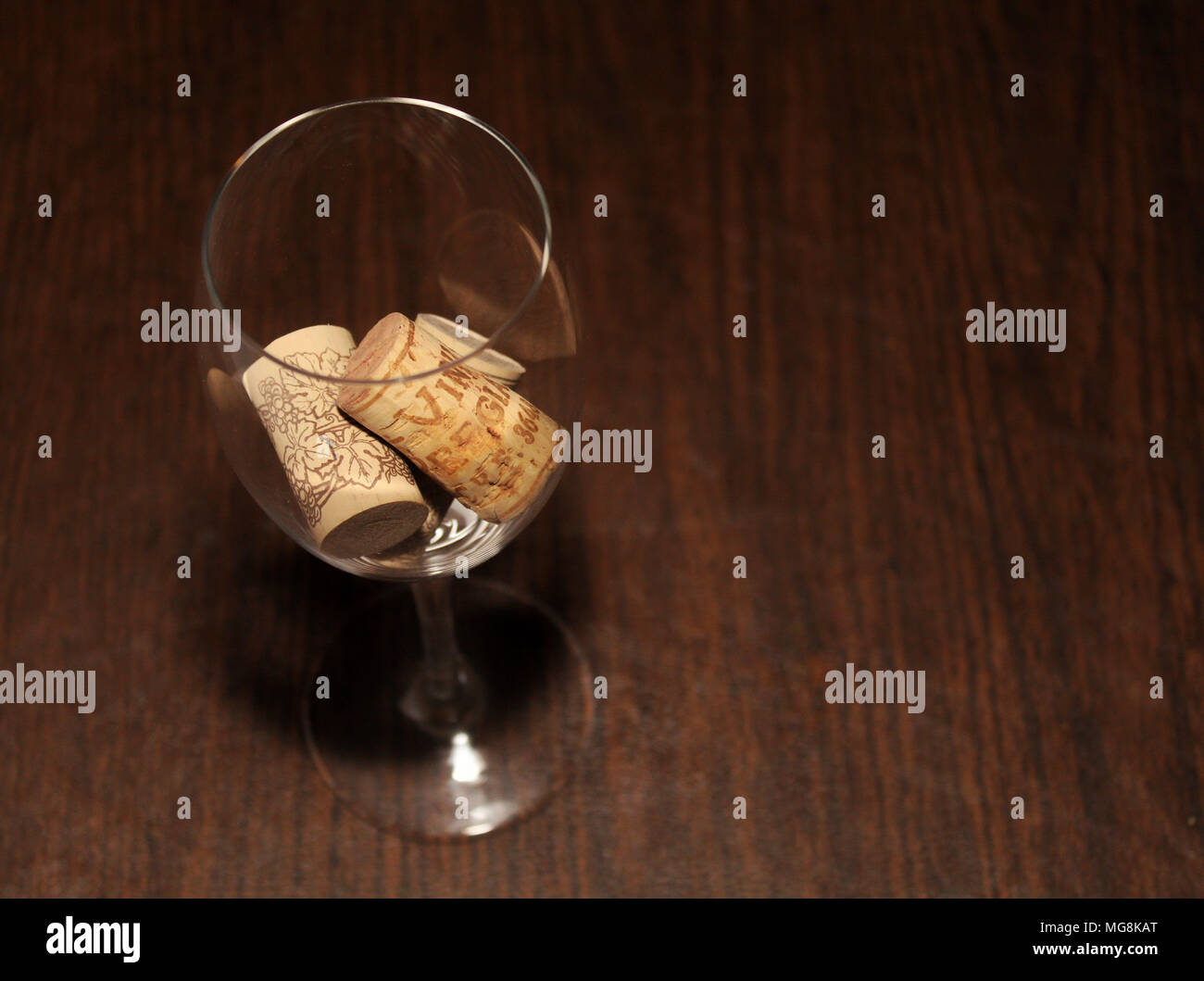 Wein Glas mit drei Korken innen auf einem Holztisch, gesehen Overhead auf der linken Seite des Rahmens Stockfoto