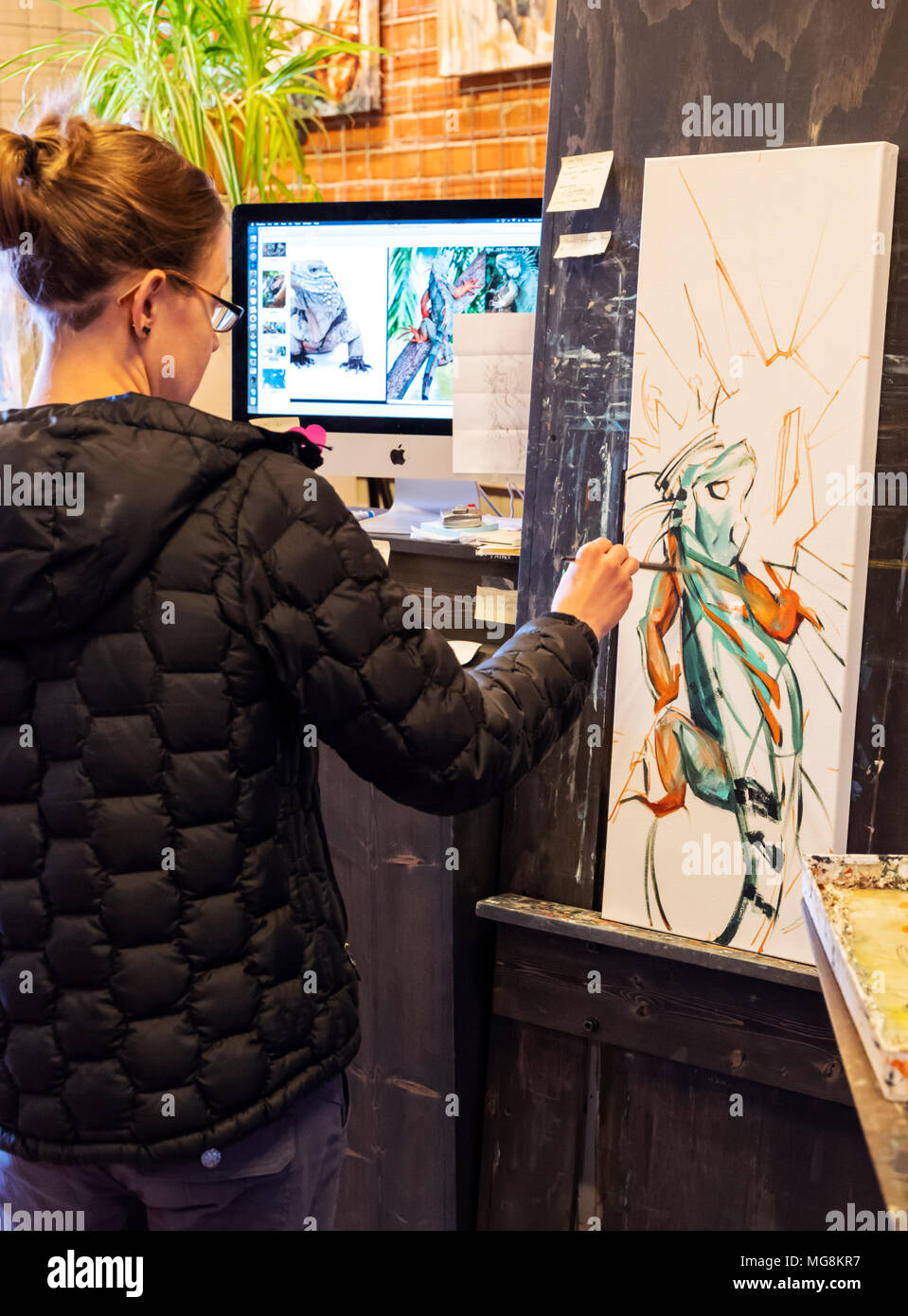 Bildende Künstlerin Katie Maher referenzieren Computer ein Bild beim Erstellen ein Ölgemälde in Ihrer Galerie; Salida, Colorado, USA Stockfoto
