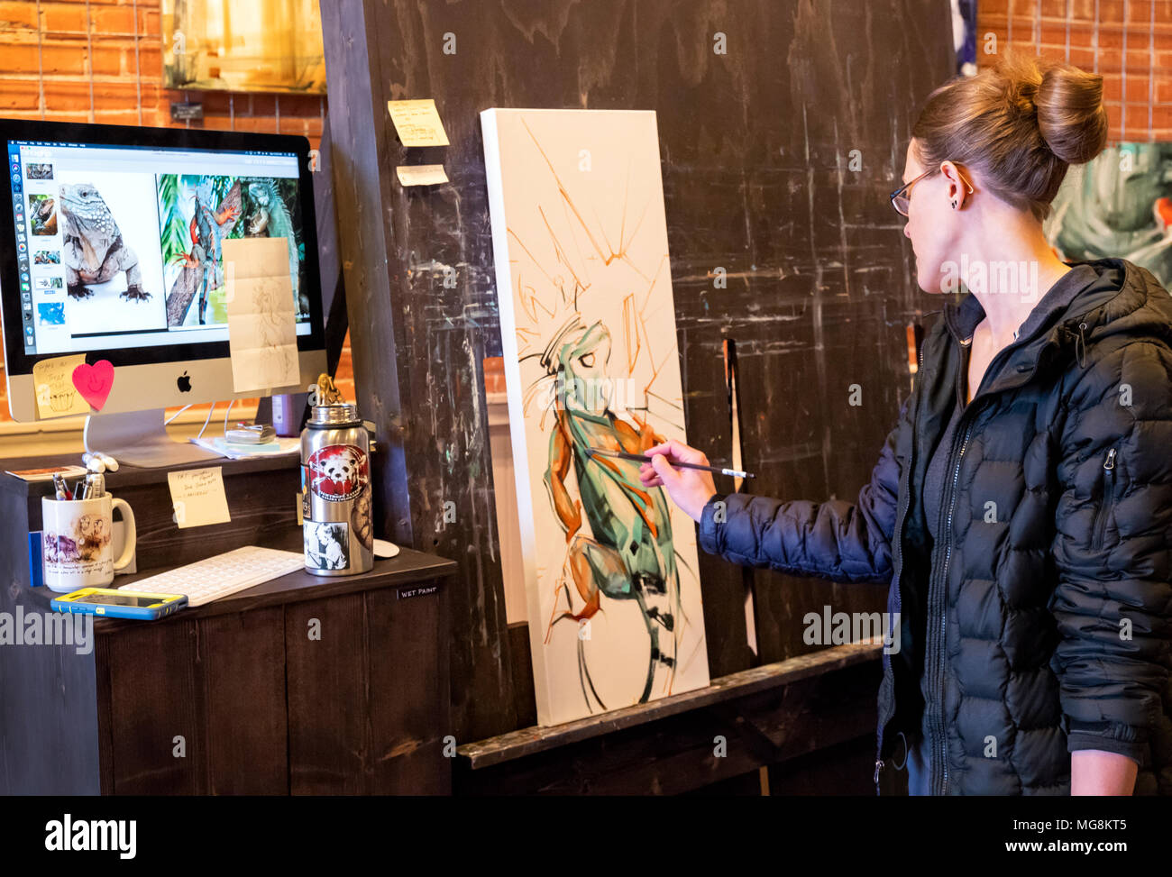 Bildende Künstlerin Katie Maher referenzieren Computer ein Bild beim Erstellen ein Ölgemälde in Ihrer Galerie; Salida, Colorado, USA Stockfoto