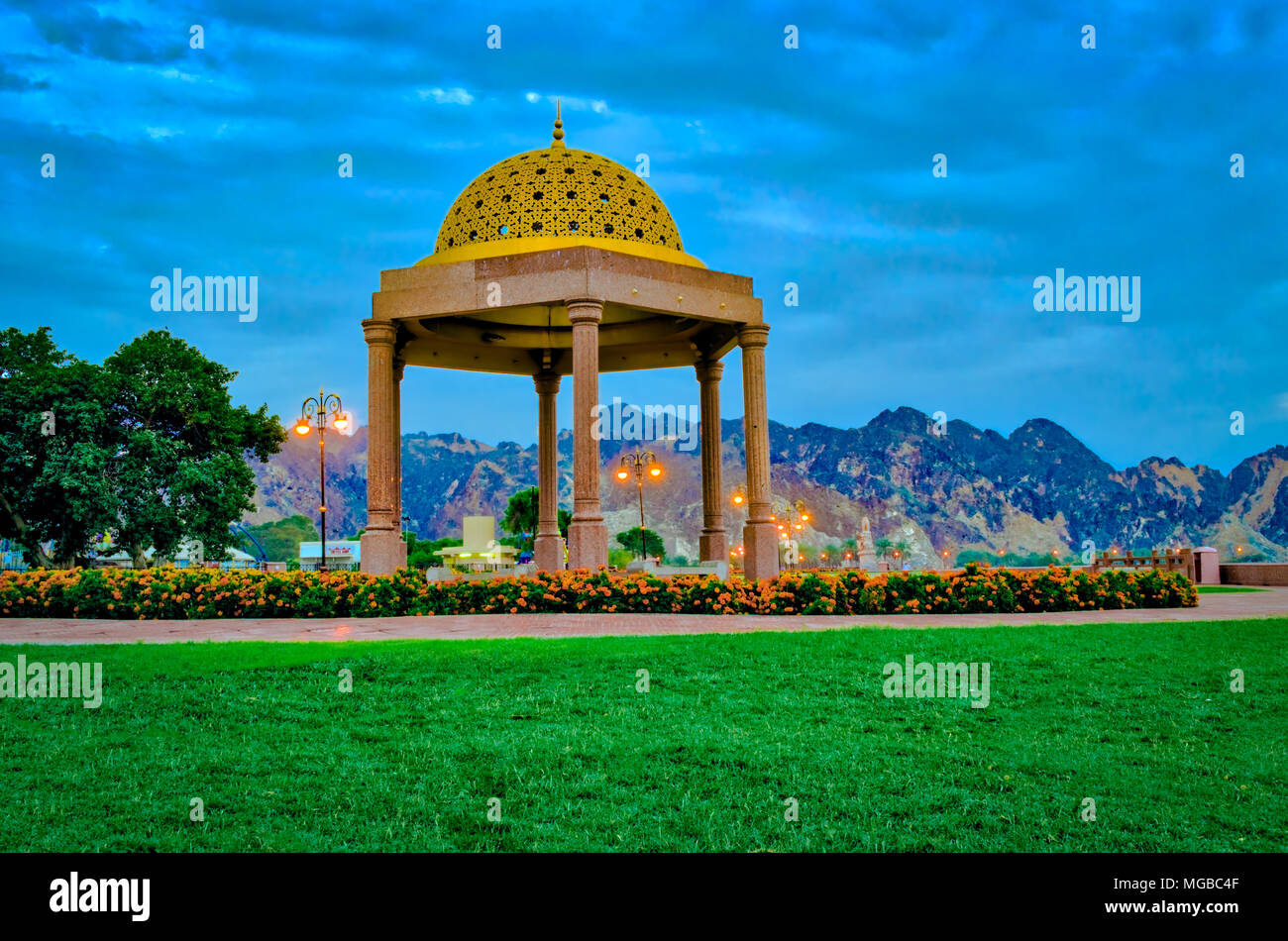 Golden Pavillon Kuppel von grünen Rasenflächen umgeben, als Ruhestätte für Menschen in der Muttrah Corniche Park, Muscat, Oman. Stockfoto