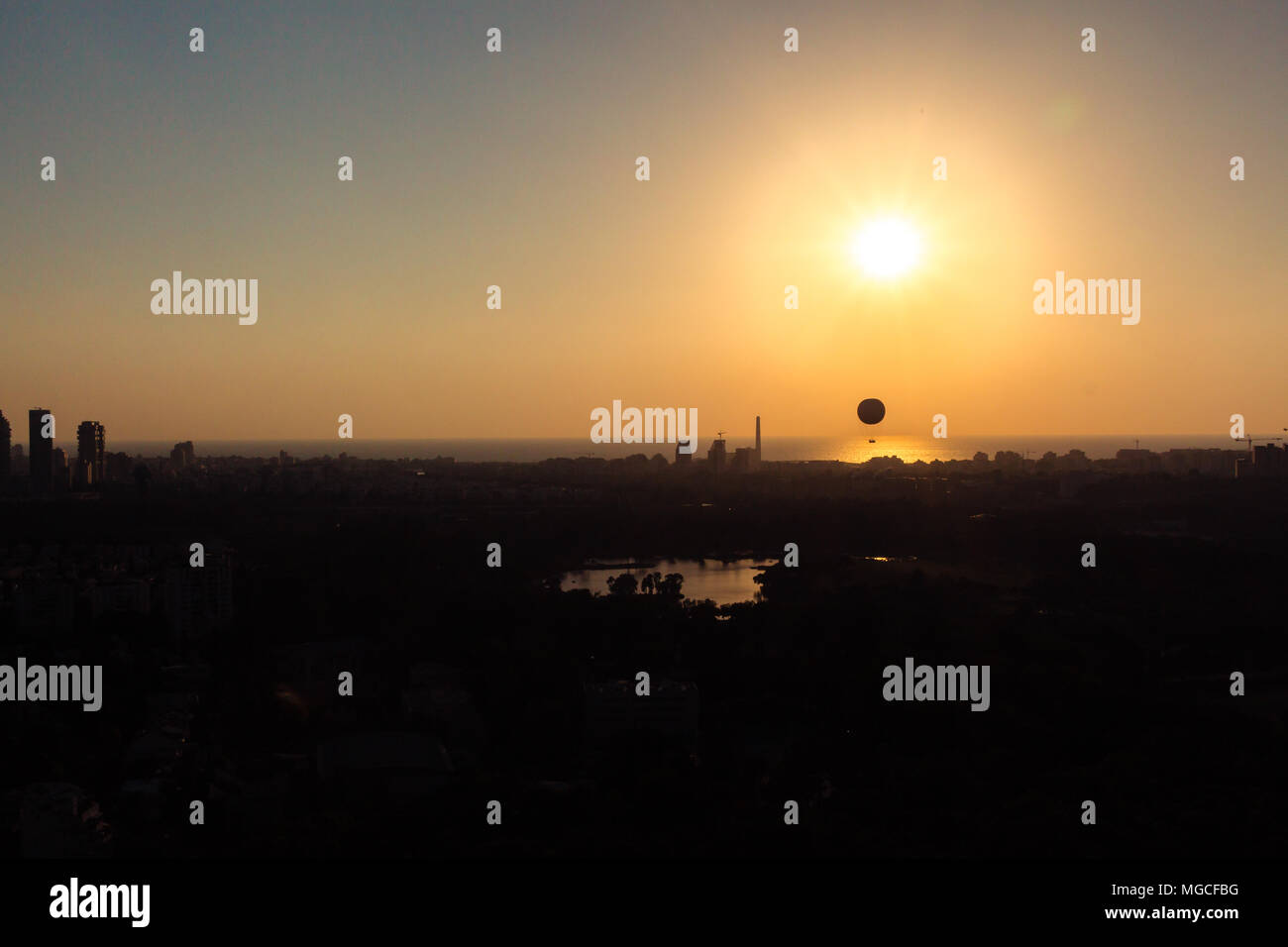 Skyline von Tel Aviv bei Sonnenuntergang - Silhouette. Sie sehen, ein Heißluftballon fliegen in der Luft. Darüber hinaus ist die Gegend im Norden von Tel Aviv sehen können, Hayarko Stockfoto