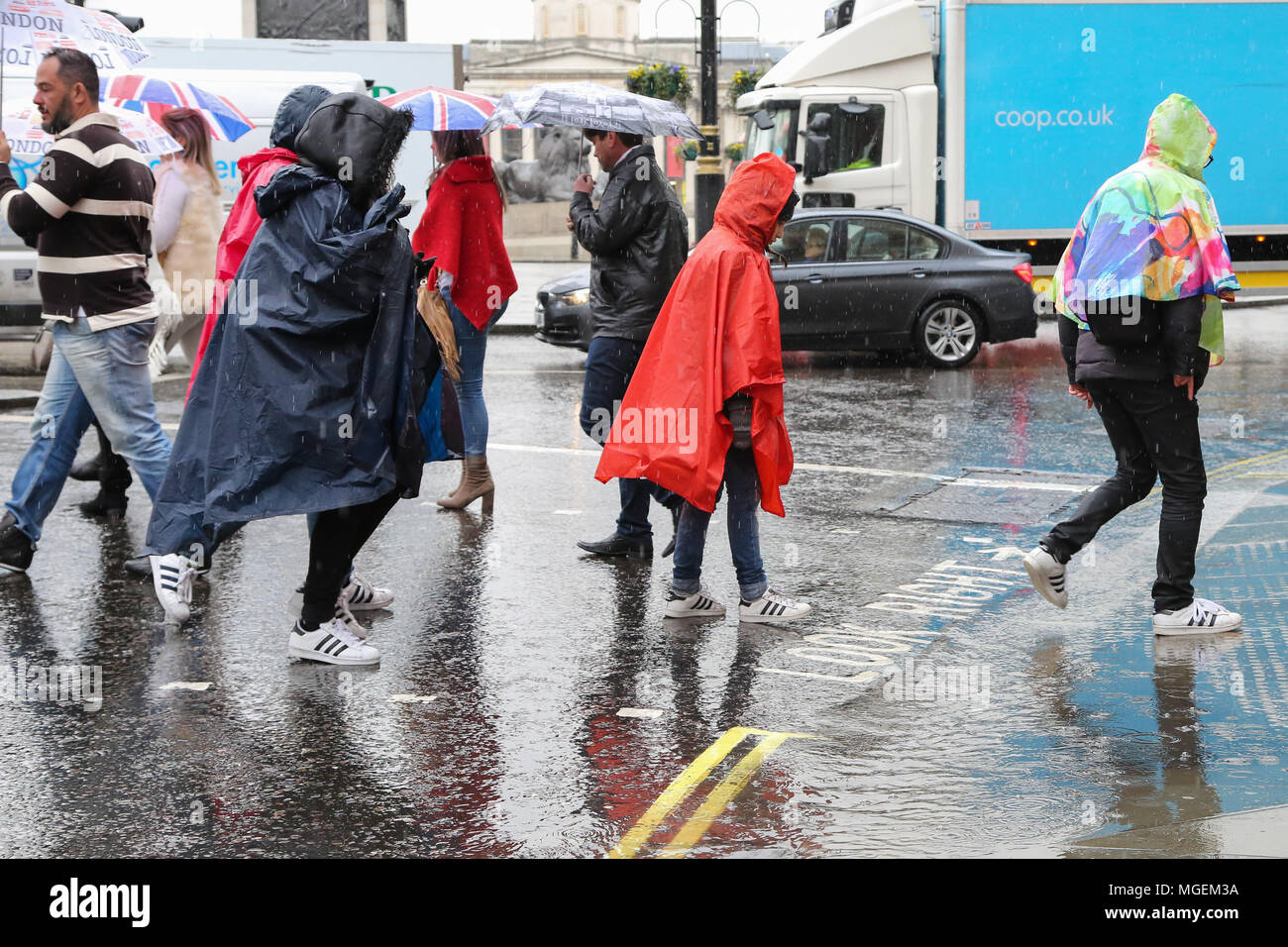 Touristen mit Sonnenschirmen und tragen Ponchos Regen im Regen, die Vermeidung von Pfütze von Regenwasser in der Nähe von Trafalgar Square bietet: Atmosphäre, Wo: London, Großbritannien Wann: 28 Mar 2018 Credit: Dinendra Haria/WANN Stockfoto