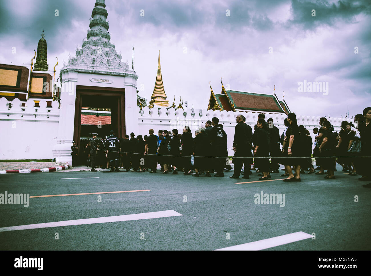 Menschen in Schwarz gekleidet in der Warteschlange, während auf der anderen Straßenseite, der Tempel Wat Phra Keo in Bangkok Stockfoto