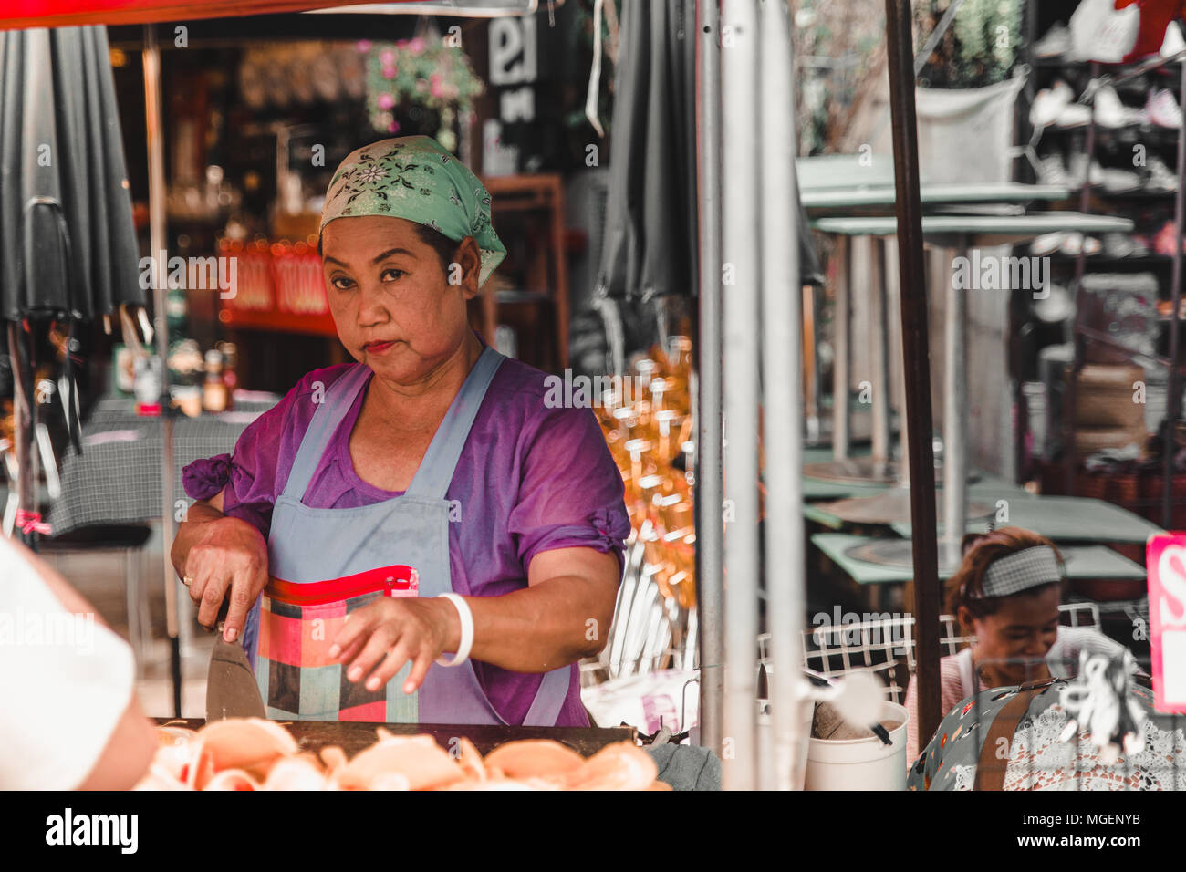 Eine alte asiatische Dame versuchen, etwas in einem der vielen Stände an der Chatuchak Markt am Wochenende zu kochen Stockfoto