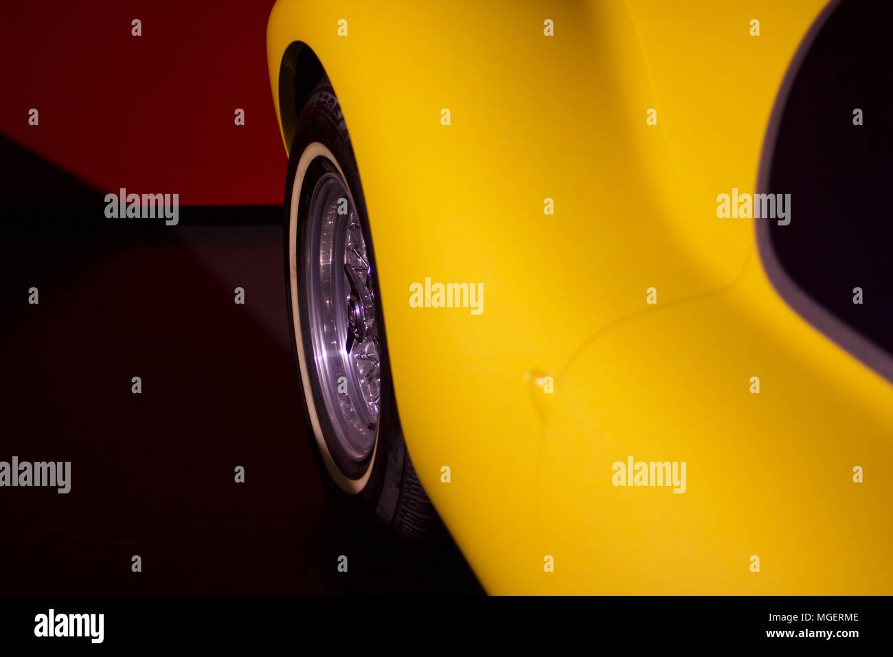 Im Vordergrund die geschwungene Kurven von einem gelben Auto, während im Hintergrund die roten Garage erscheint unscharf Stockfoto
