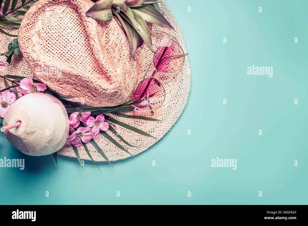 Sommer Urlaub. Strand Zubehör: Strohhut, Palm Blätter, rosa Sonnenbrille, Blumen und Kokospalmen Cocktail auf blau türkis Hintergrund, Ansicht von oben. Tr Stockfoto