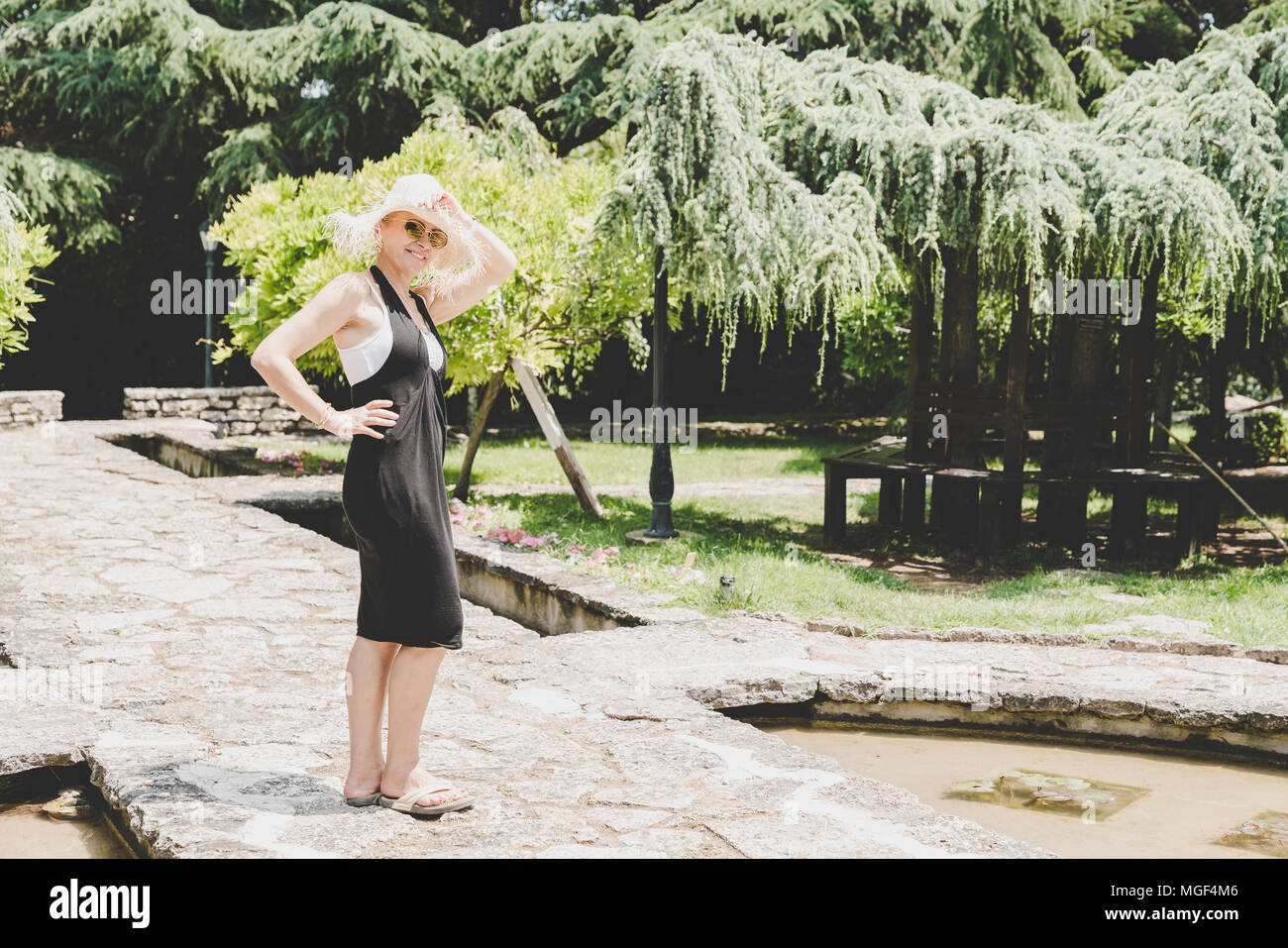 Gerne schöne Frau genießt Sommertag in einem Garten Stockfoto