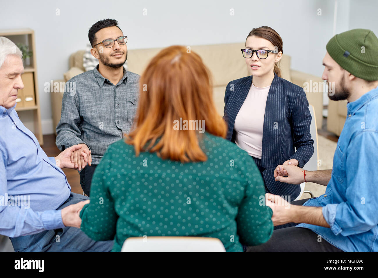 Gruppe von Patienten mit phobien im Kreis sitzen und halten sich an den Händen, während talentierte Psychologe Durchführung Sitzung, Interieur des gemütlichen Büro o Stockfoto