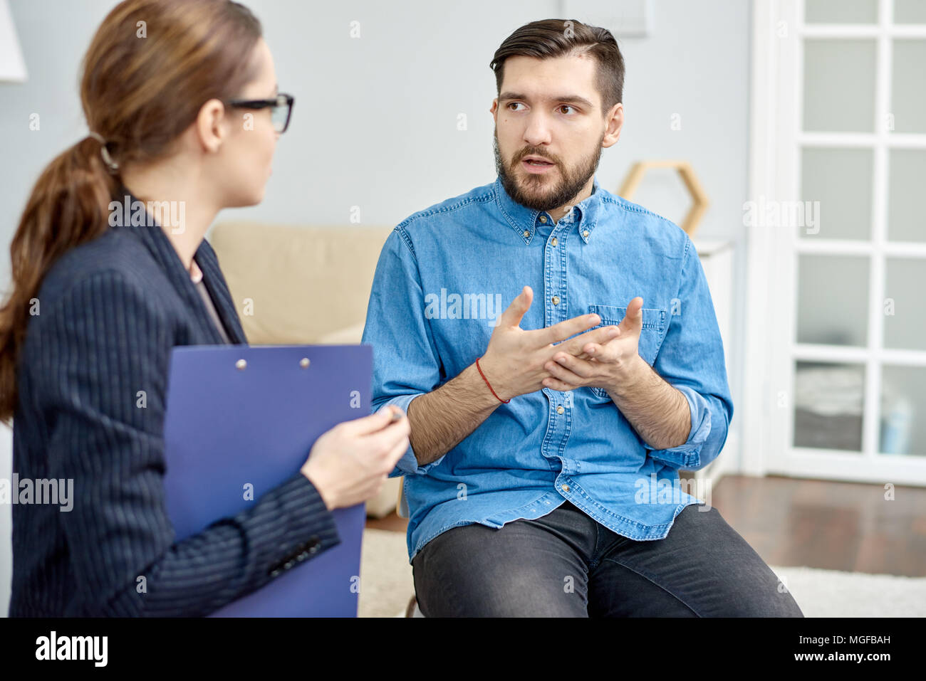 Schöne bärtige Patient, der Mangel an sozialen Fähigkeiten, die versuchen, das Problem mit Hilfe von hoch professionellen Psychologen zu lösen, Interieur des gemütlichen Büro o Stockfoto