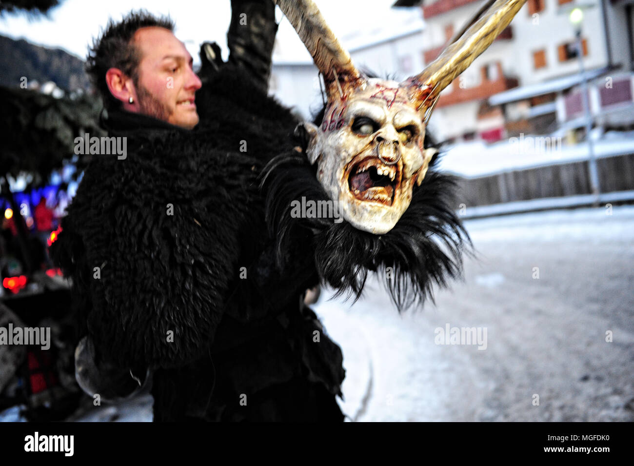 Ein Mann wird von einem krampus Maske vor der Teilnahme an der traditionellen Parade in der Stadt von Kastelruth (Kastelruth), Italien zu tragen Stockfoto