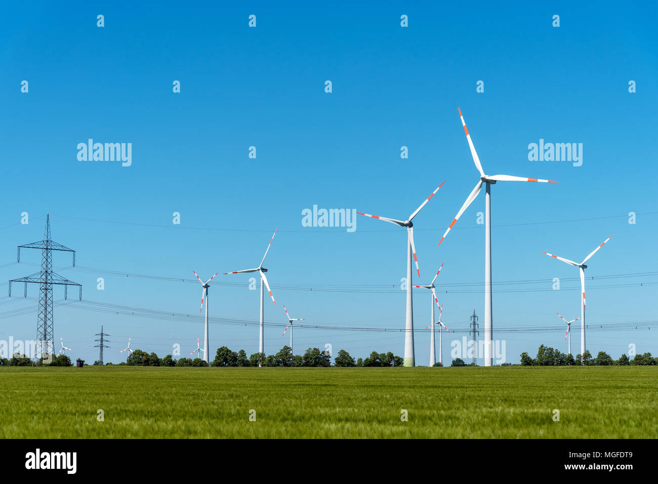 Freileitungen und Windkraftanlagen unter einem blauen Himmel in Deutschland Stockfoto