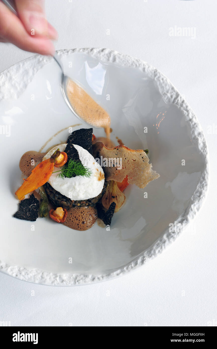 Das mit einem Michelin-Stern ausgezeichnete Küchenchef Régis Marcon stellt den letzten Schliff auf seine "ragoût de lentilles Vertes de Puy avec Truffes et oeuf de Poule fumé' Stockfoto