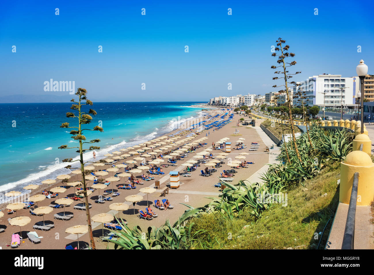 Ägäis Strand mit Sonnenschirmen in der Stadt Rhodes (Rhodos, Griechenland) Stockfoto