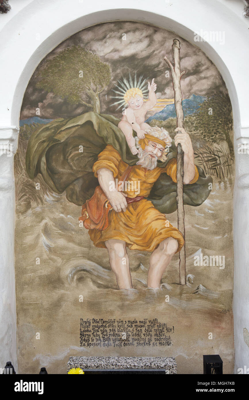 Saint Christopher Durchführung der Christus Kind. Wandmalerei in der Grabkapelle auf dem Dorffriedhof in Albrechtice nad Vltavou in Südböhmen, Tschechien. Beerdigung Kapellen auf dem Friedhof an der Wand platziert wurden mit Wandmalereien in den 1840er Jahren von den lokalen Malers František Mikule mit Pfarrer Vít Cíza, der auch Gedichte für jedes Wandbild aus durchgeführt. Die Wandmalereien wurden mehrmals während des 19. und 20. Jahrhundert neu gestrichen und vollständig von dem Team unter der Leitung von Jitka Musilová in 2010-2013 restauriert. Stockfoto