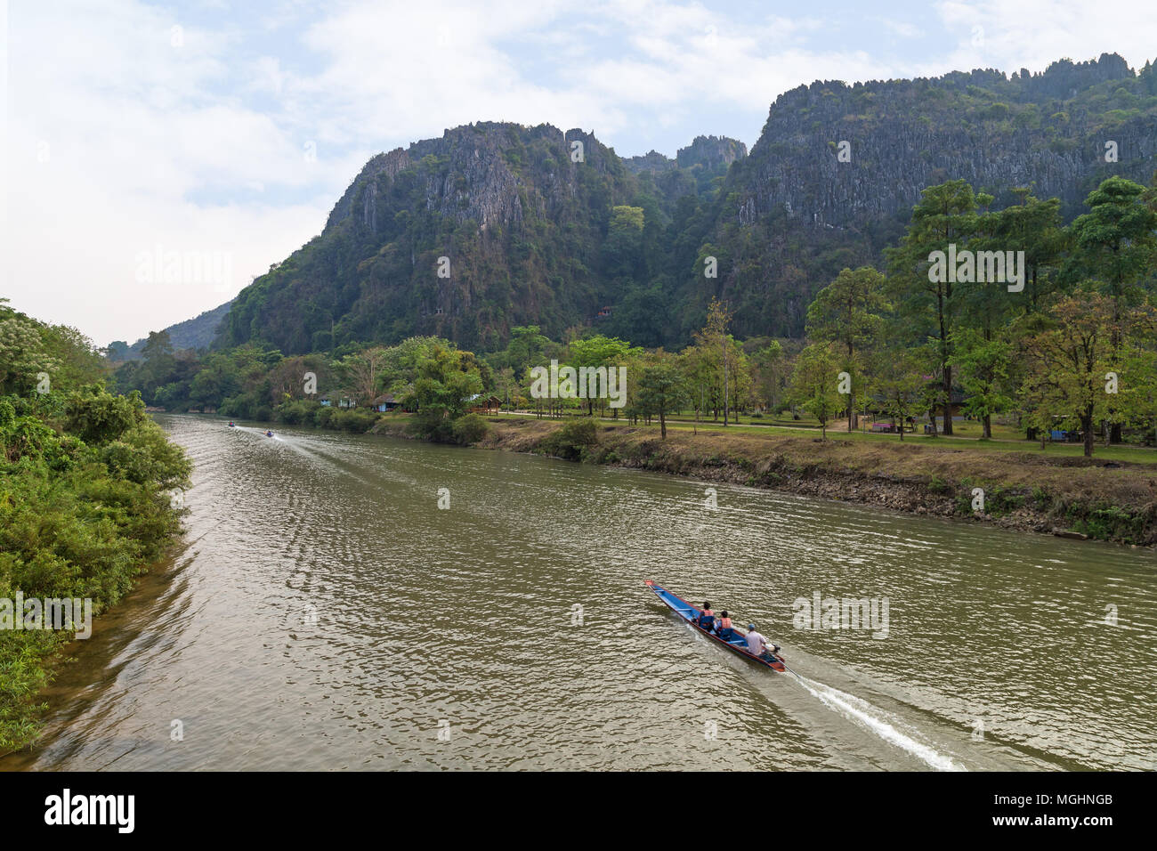 Blick auf drei kleine Boote auf dem Fluss Nam Song und Kalkstein Karst Bergen nahe der Tham Chang (oder Jang oder Jung) Höhle in Vang Vieng, Laos. Stockfoto