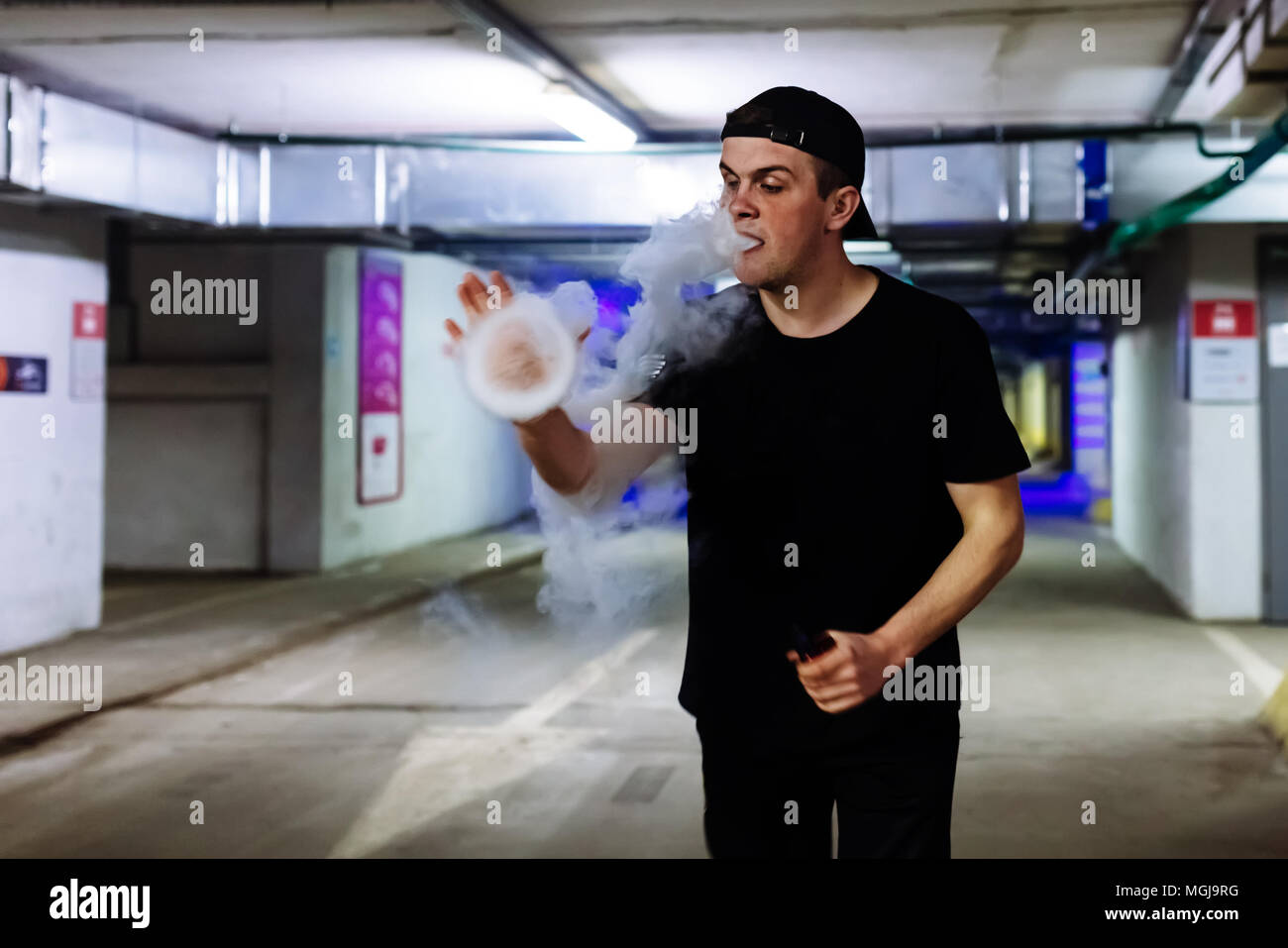 Mann in Gap Rauch eine elektronische Zigarette und Releases Wolken von Dampf Ausführen verschiedener Art vaping Tricks Stockfoto