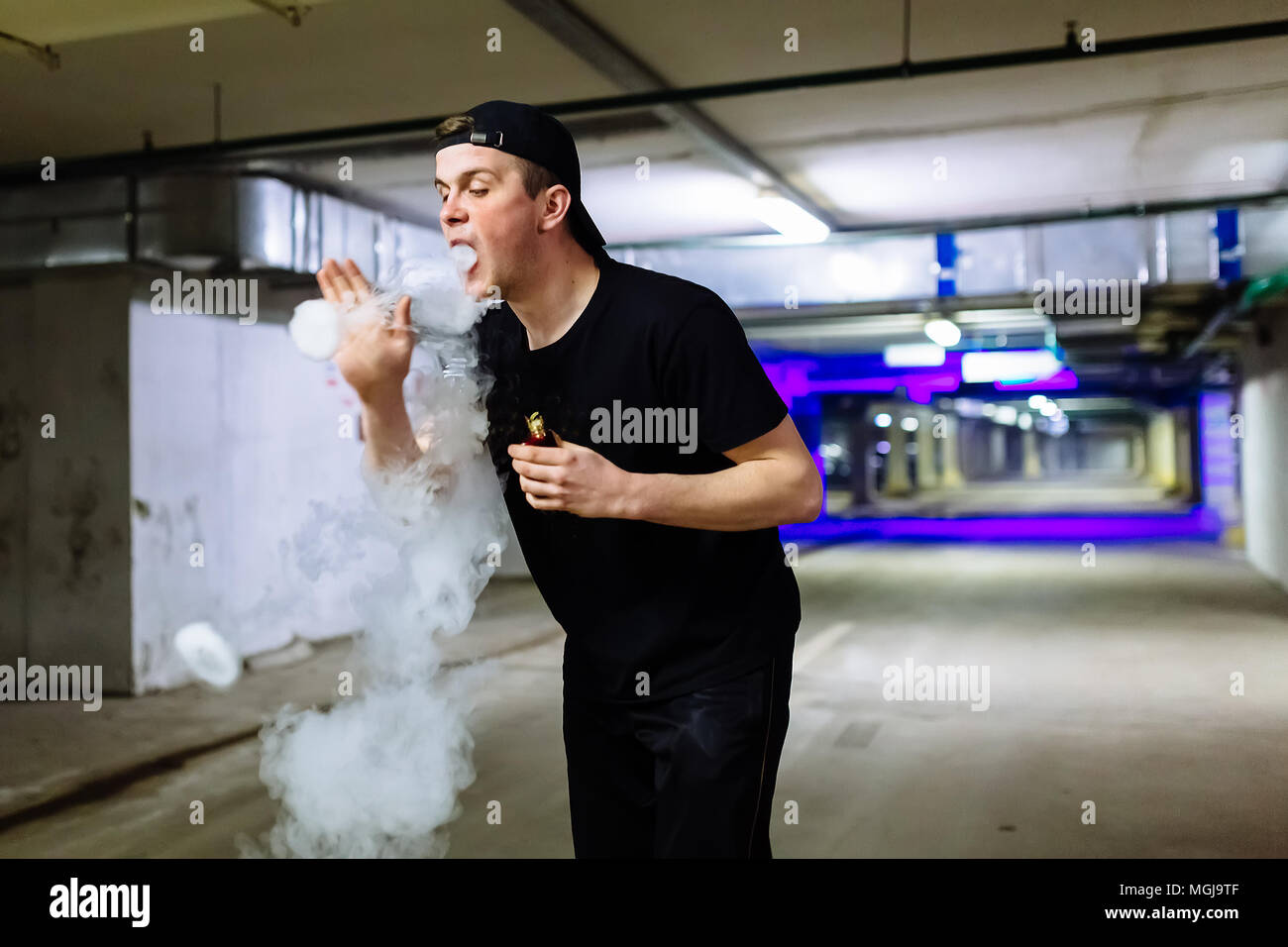 Mann in Gap Rauch eine elektronische Zigarette und Releases Wolken von Dampf Ausführen verschiedener Art vaping Tricks Stockfoto