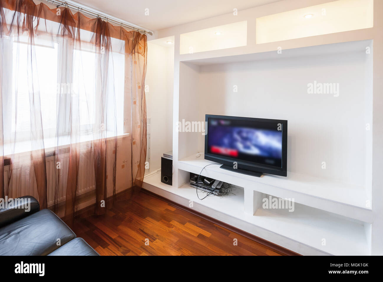 Leere Zimmer Einrichtung mit schwarzen Sofa und Tv in weiße Wand installation Stockfoto