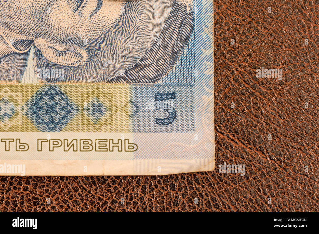 Kiew, Ukraine - Dezember 19, 2014: Ukrainische Papiergeld, Griwna, legt auf Braunes Kunstleder mit Mustern. Teilweise Makro Foto von der Ecke der Banknote. Bill von fünf Stockfoto