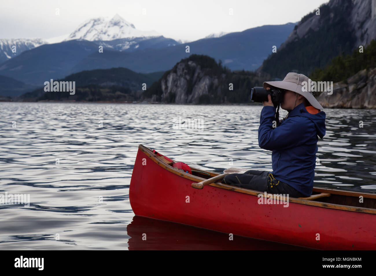 Männliche Fotografen auf ein hölzernes Kanu ist, die Bilder von der schönen kanadischen Bergwelt. In Squamish, nördlich von Vancouver, BC, Kanada Stockfoto