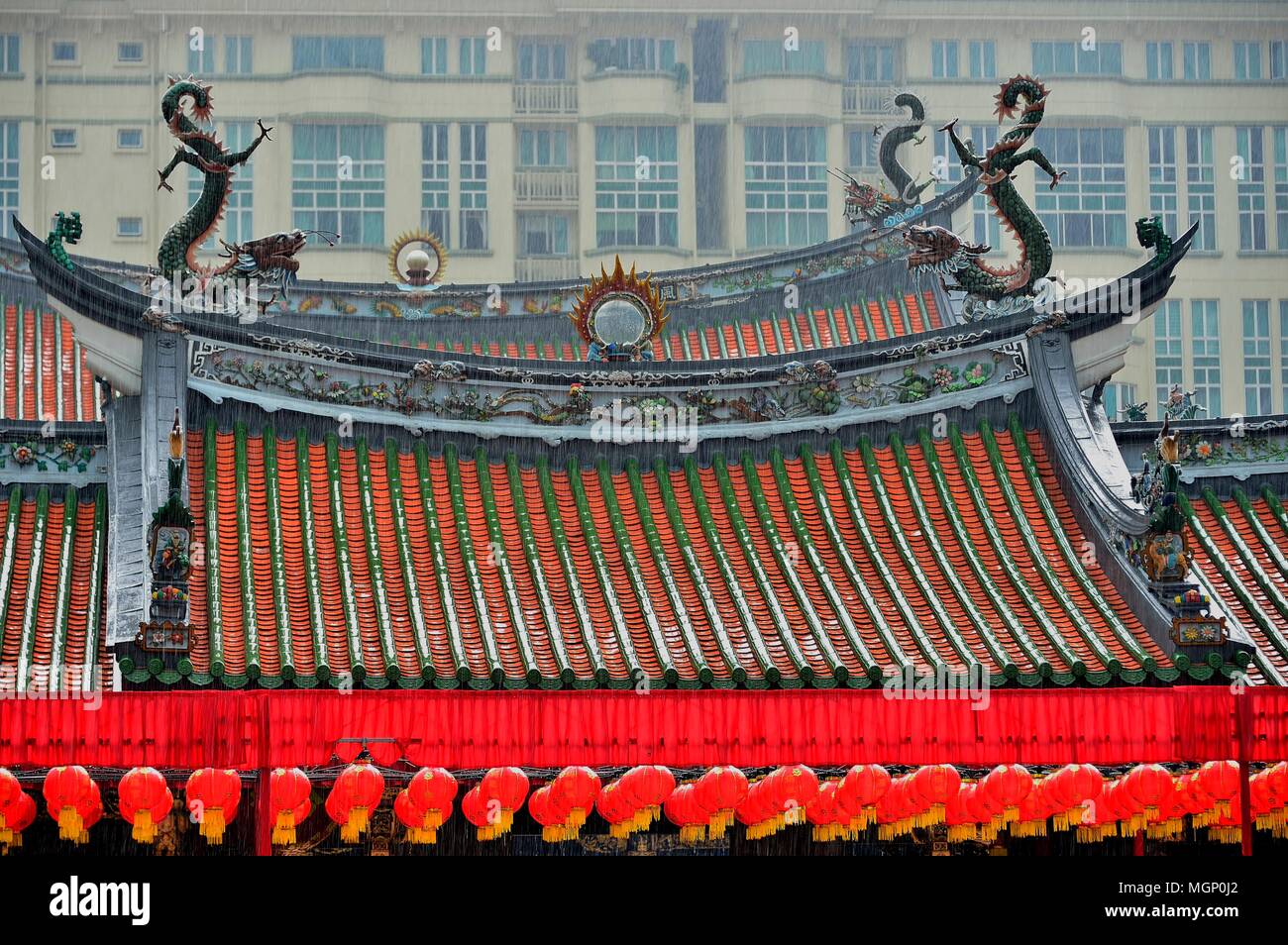 Vorderansicht des berühmten alten chinesischen buddhistischen oder taoistischen Tempel Dach mit ornamentalen Schnitzereien und roten Laternen im Regen in der Innenstadt von Singapur Stockfoto