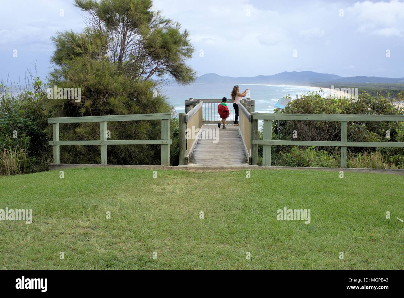 Touristen am Aussichtspunkt in Nambucca Heads in New South Wales, Australien. Kind, Frau Bilder aufnehmen mit Ihrem Mobiltelefon von der Landschaft des Meeres. Stockfoto