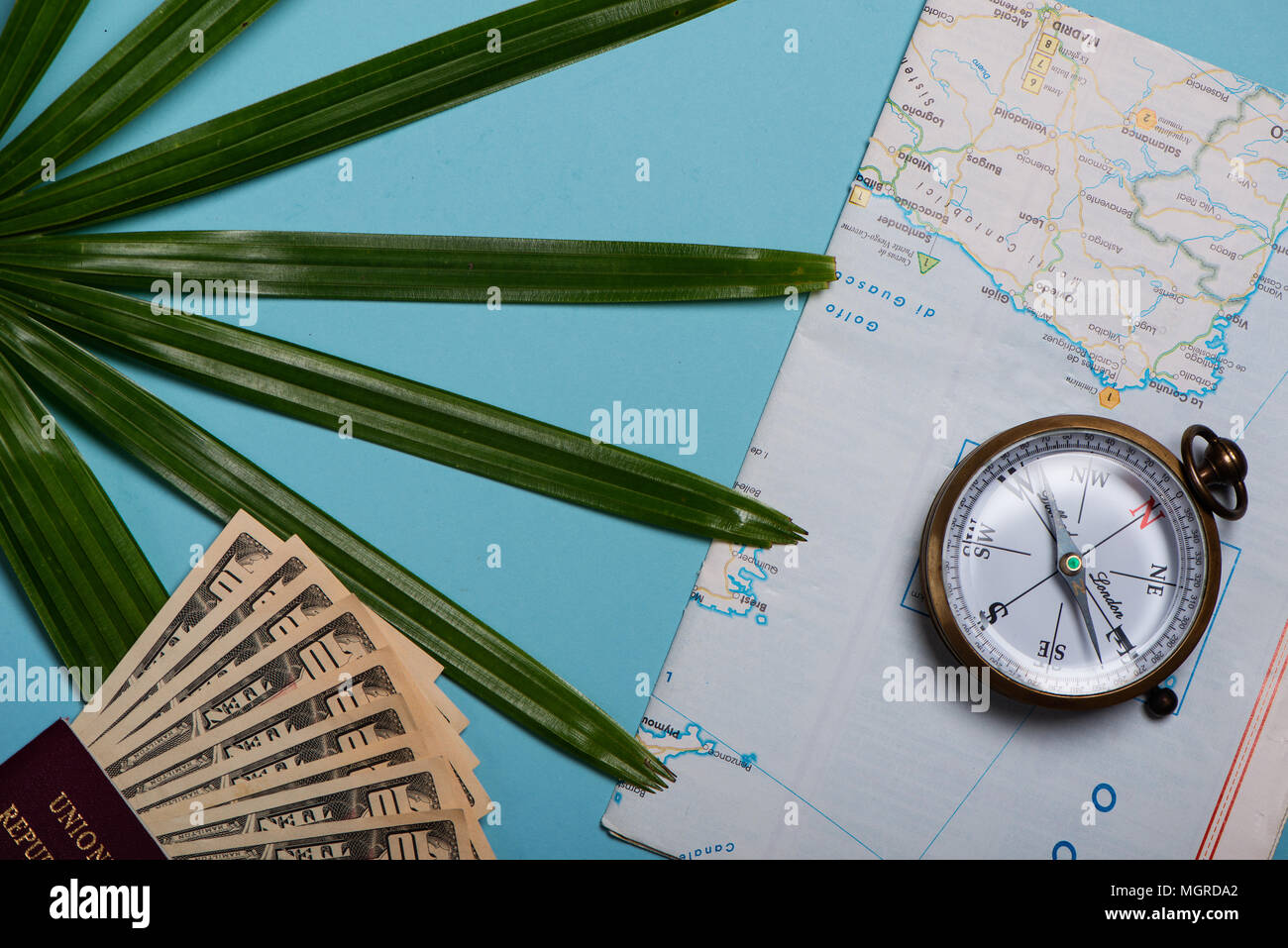 Reisen Vorlage Ansicht von Oben. Weltkarte, Reisepass, Dollar, Kompass, Palmen Blatt auf blauem Hintergrund Stockfoto