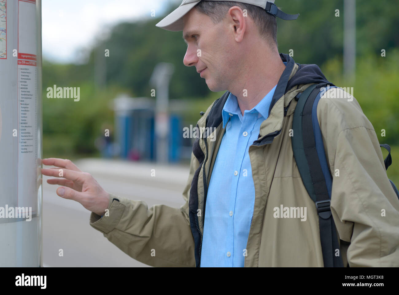 Mann beim Lesen des Fahrplans an einer Bushaltestelle in den Niederlanden Stockfoto