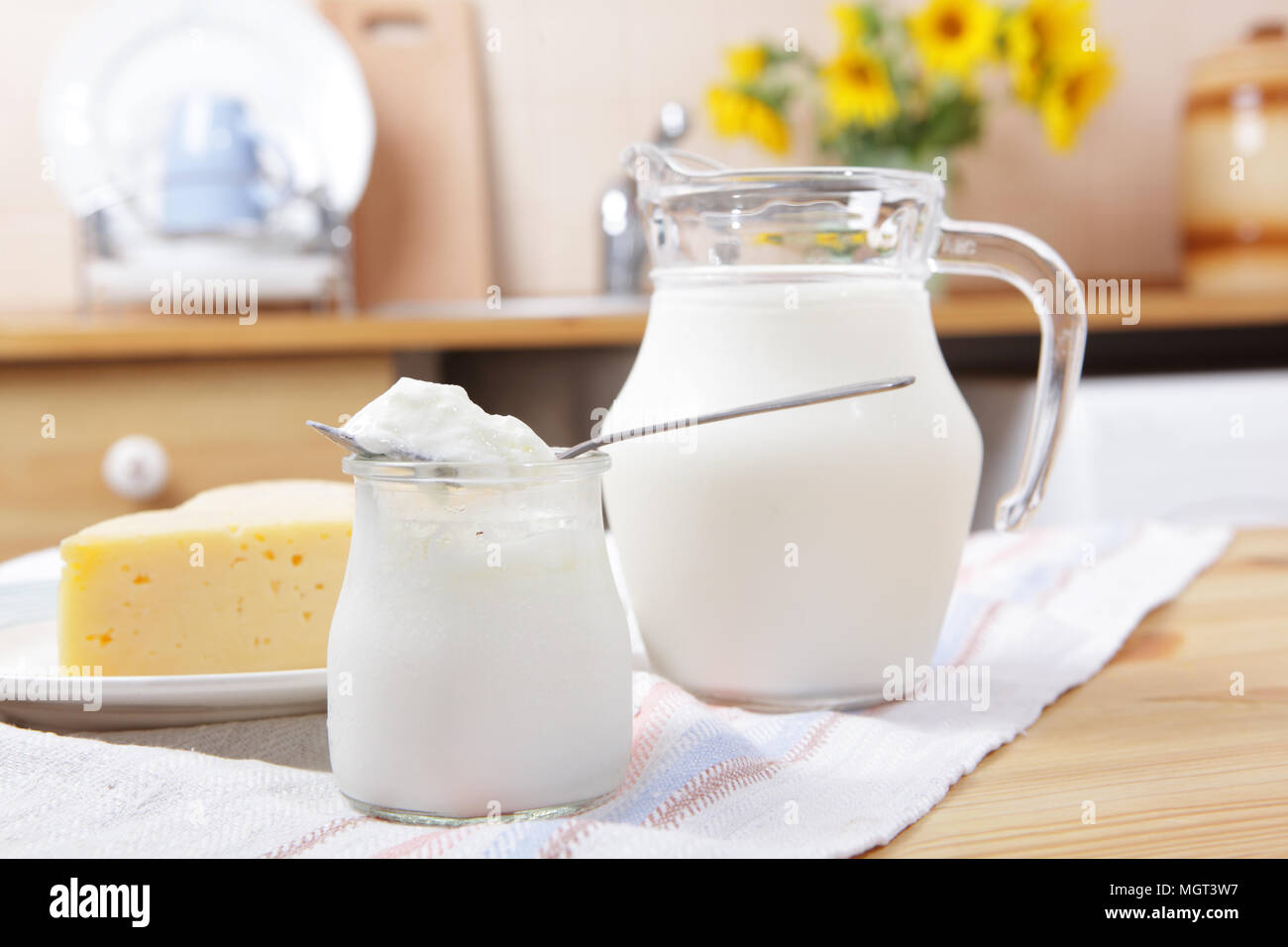 Joghurt, gelben Käse, und die Kanne von Milch auf einem Küchentisch Stockfoto