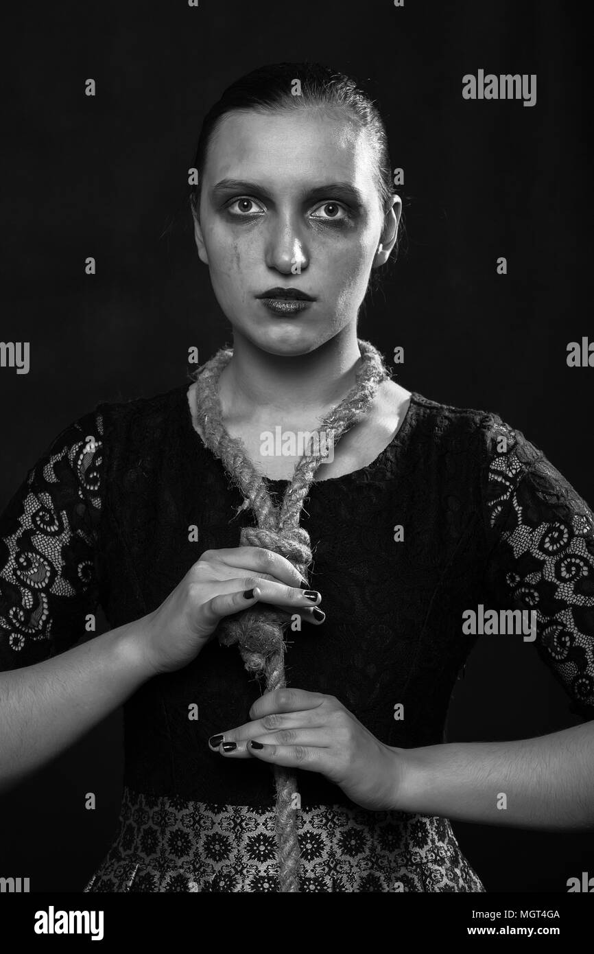 Traurige junge Frau mit Schleife auf Dunkelroten Hintergrund auf Kamera, Monochrom Stockfoto