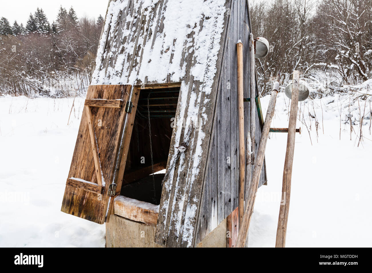 Öffnen Sie gut am Rande des Waldes in russischen Dorf mit alten Typische Werkzeuge (Eispickel und Pfannen) bei bedecktem Wintertag in Smolensk region Russ Stockfoto