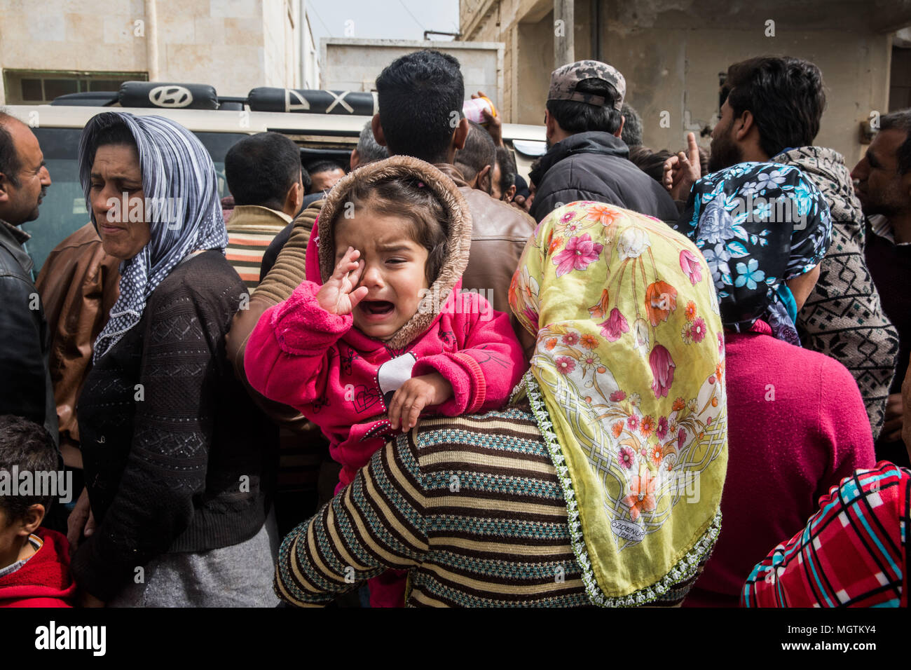 Ein Kind schreit wie ihre Mutter wartet, Beihilfen aus den kurdischen Roten Halbmond in hohen Ri" Fett zu erhalten. Schätzungsweise 400.000 Flüchtlinge auf der Flucht vor den zwei Monate alten türkischen militärischen Kampagnen in ein rund 400 Quadratkilometer Fläche innerhalb Metropole Provinz im nördlichen Syrien vertrieben wurden. Zentrale Metropole ist der Flammpunkt Stadt groß Ri" Fett, wo schätzungsweise 75.000 Flüchtlinge in zerstörten Häusern, die zuvor von islamischen Kämpfern besetzten niedergelassen haben. Die umliegenden Dörfer jetzt Gehäuse die Vertriebenen mit Minen und IEDs Überbleibsel aus dem Konflikt übersät sind. Zehntausende von Flüchtlingen Stockfoto