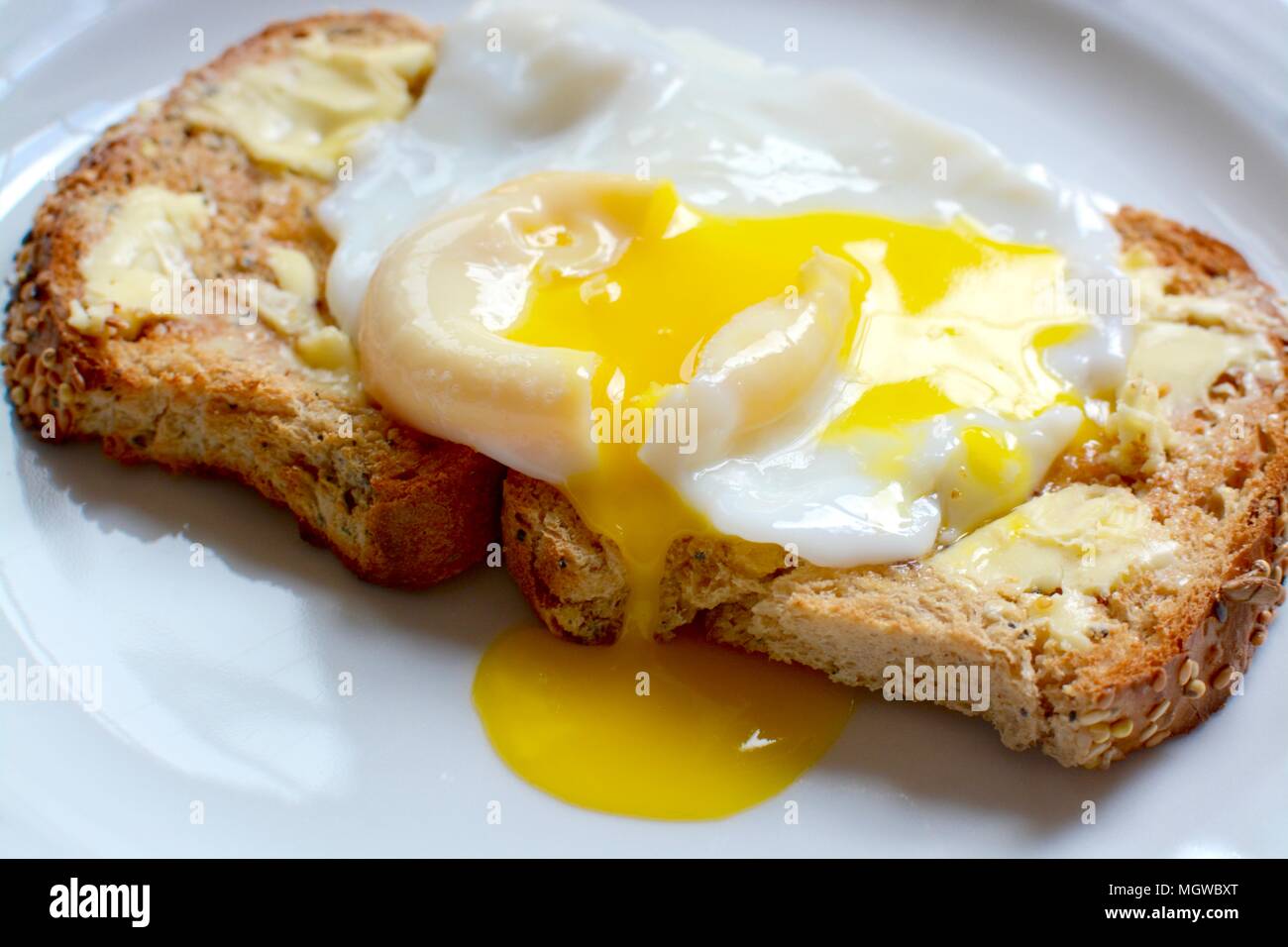Perfekte Runny pochiertem Ei auf Braun gesäte Toast Stockfoto