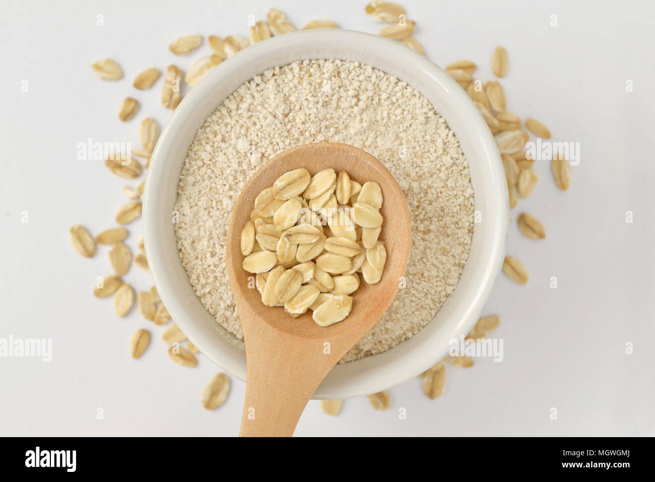 Haferflocken auf Holzlöffel und Hafer Mehl in Schüssel Stockfoto